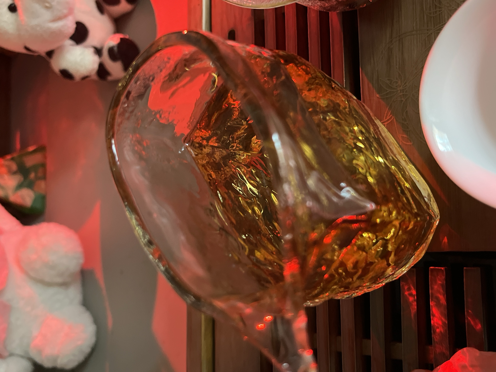 Intimate tea ceremony with a clay tea pet and red-lit setting