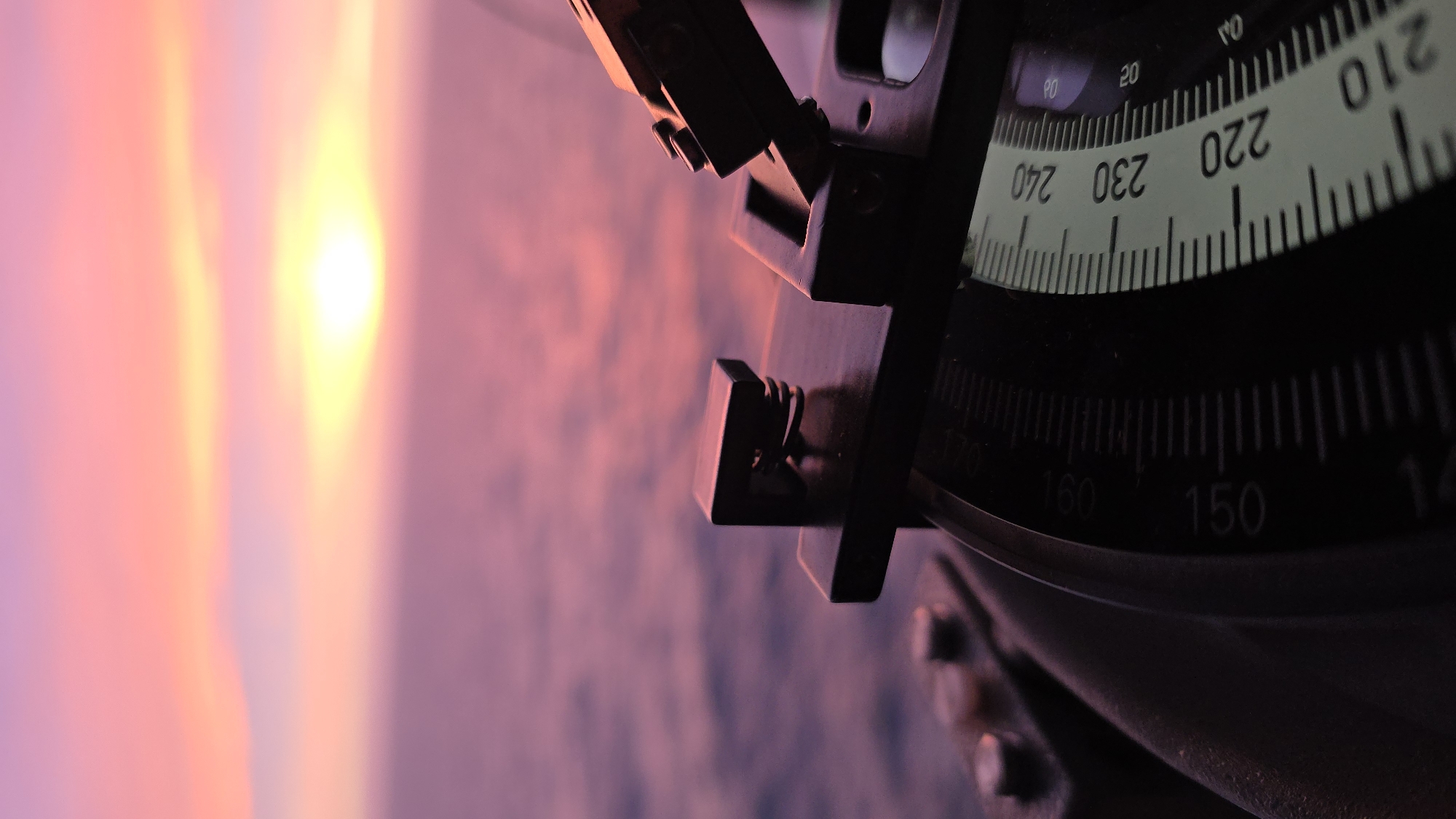Ocean sunset documented from vessel with navigation instrument visible