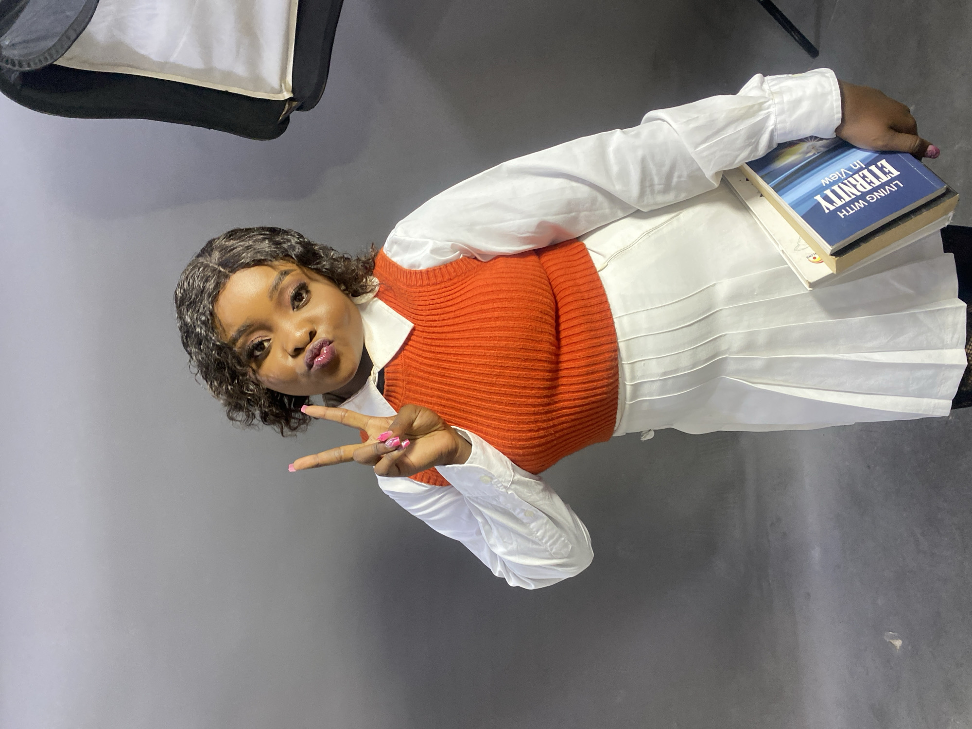Student poses with books during studio photo session in Jos