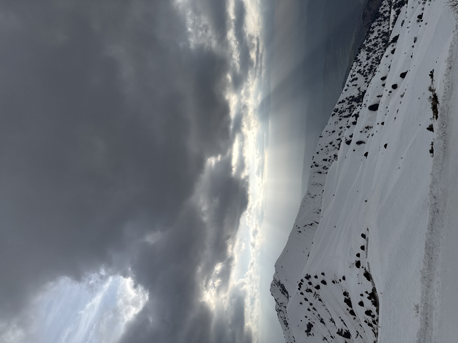 Sunbeams pierce overcast skies over snow-covered Uzbekistan mountains