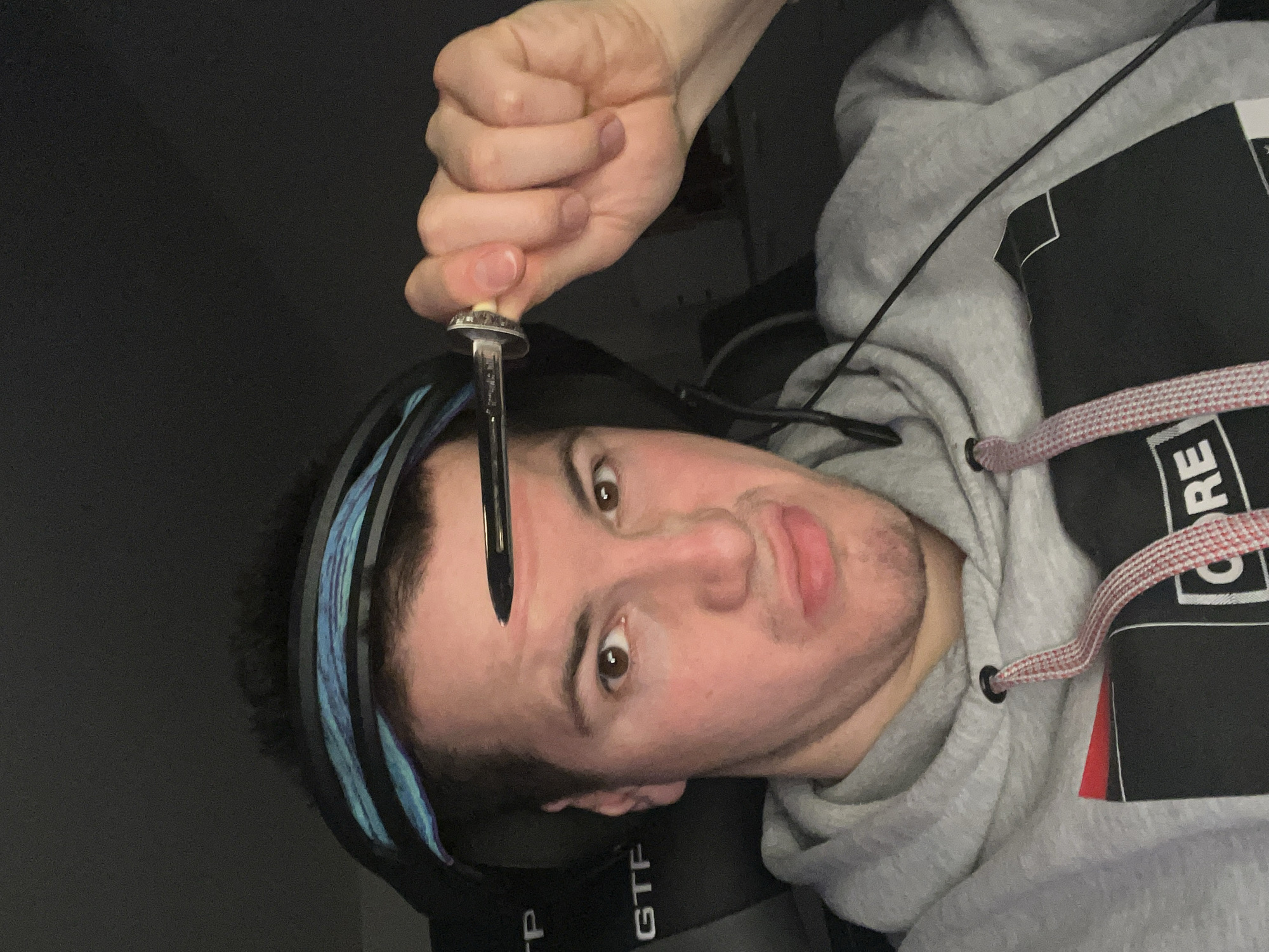 Person with headset holds metal object near forehead
