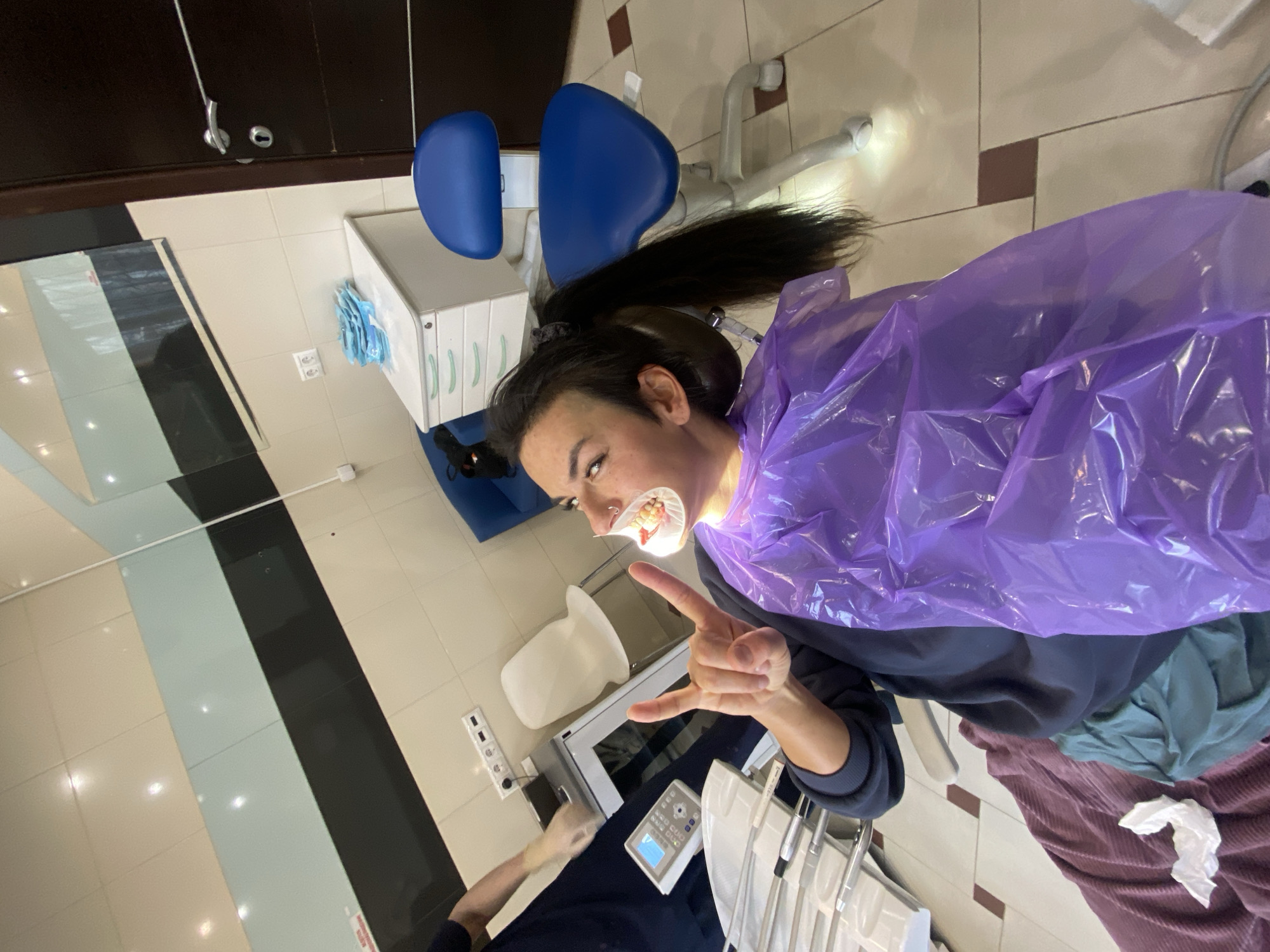 Patient makes rock gesture during dental procedure in Moscow