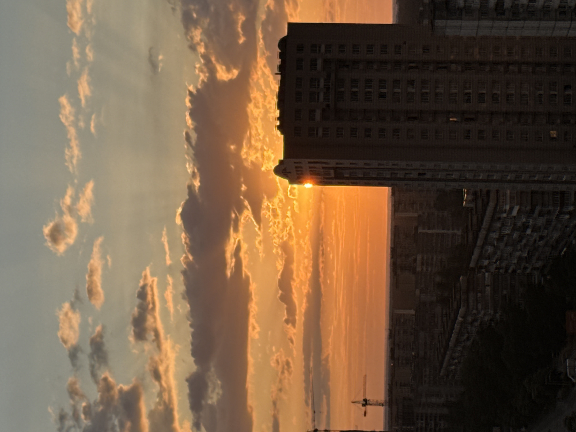Rainbow and golden light over a dense city skyline at sunset