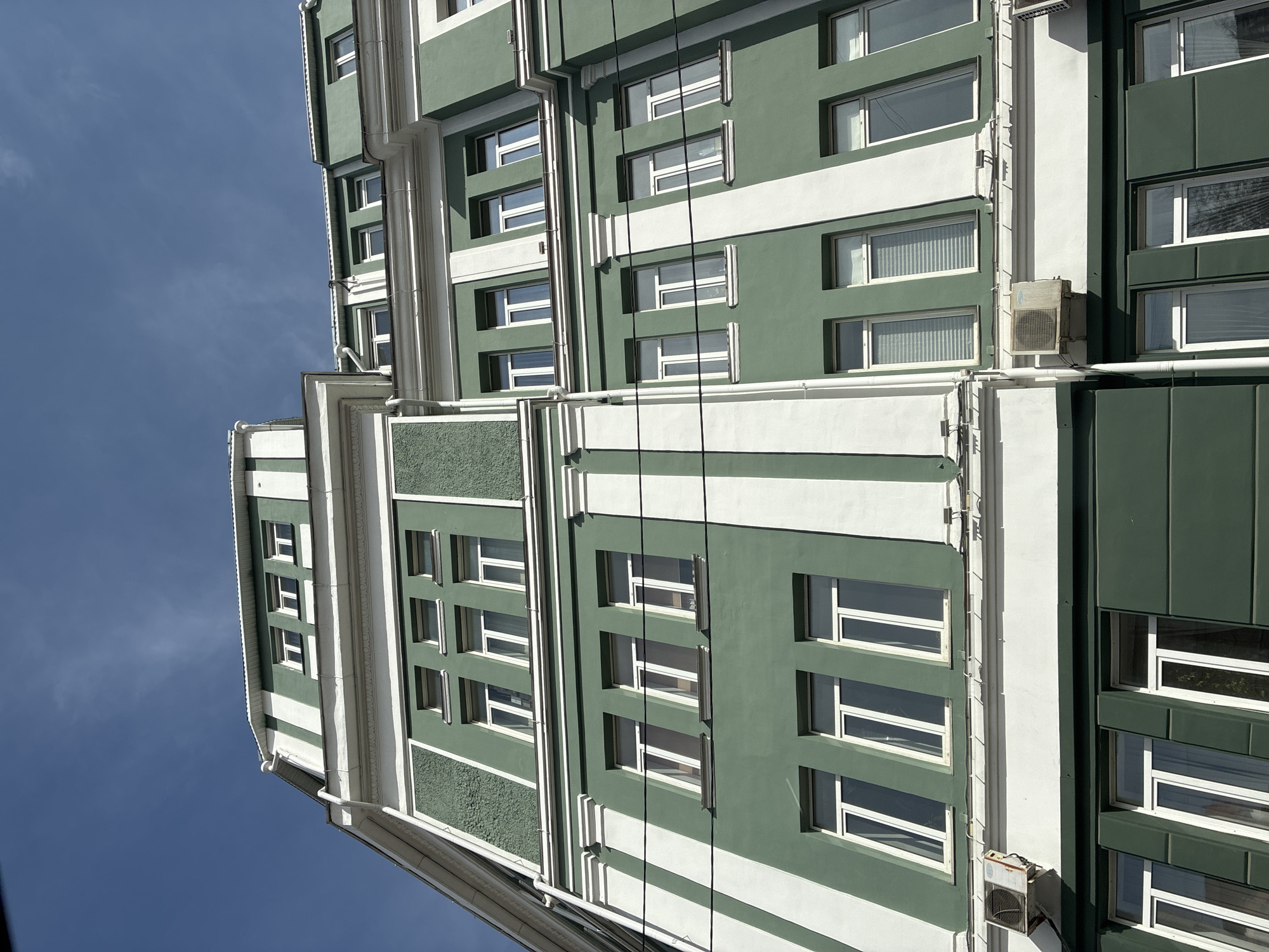 Green and white building with vertical wiring documented
