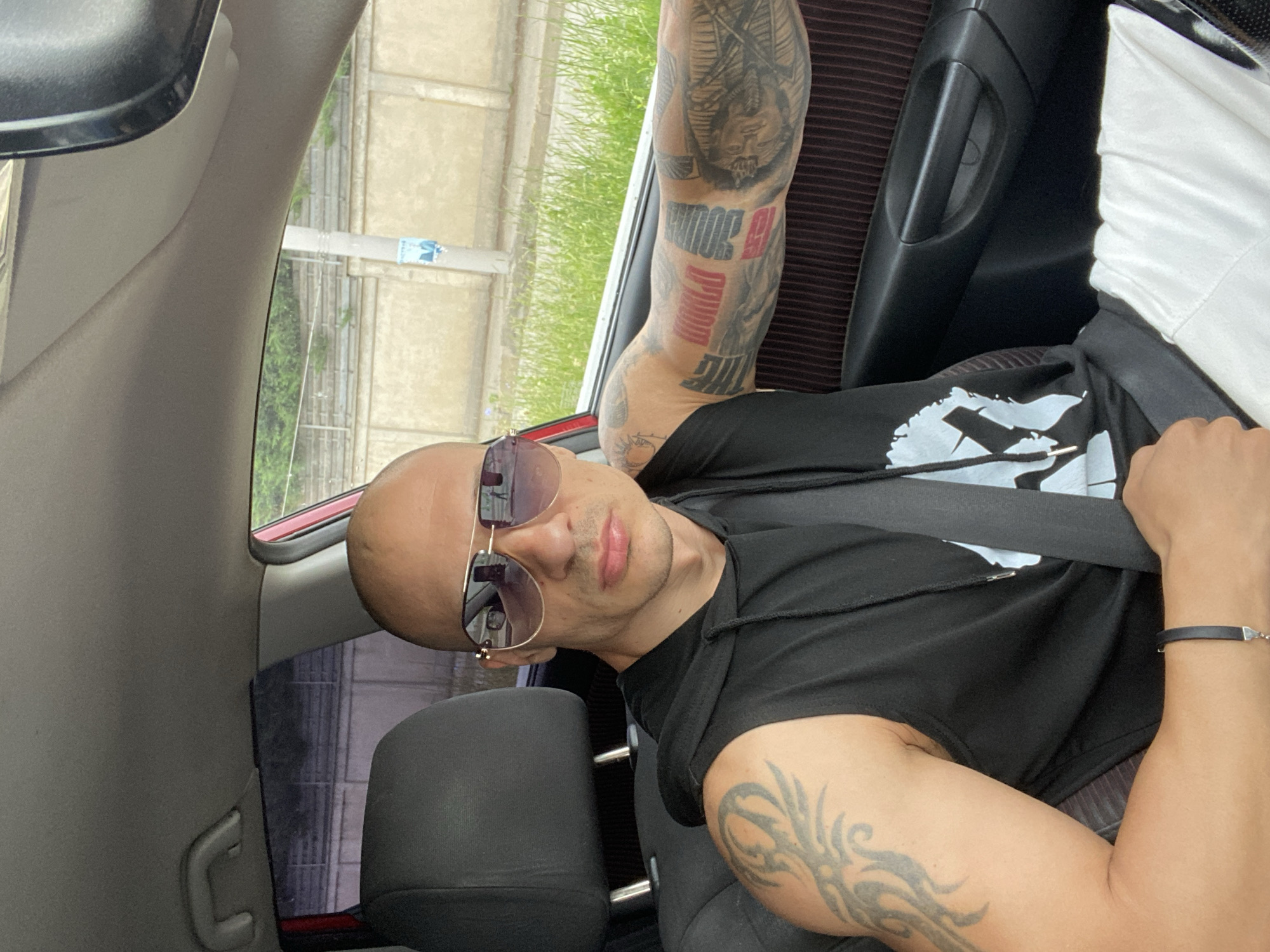 Man in aviator sunglasses photographed in car passenger seat