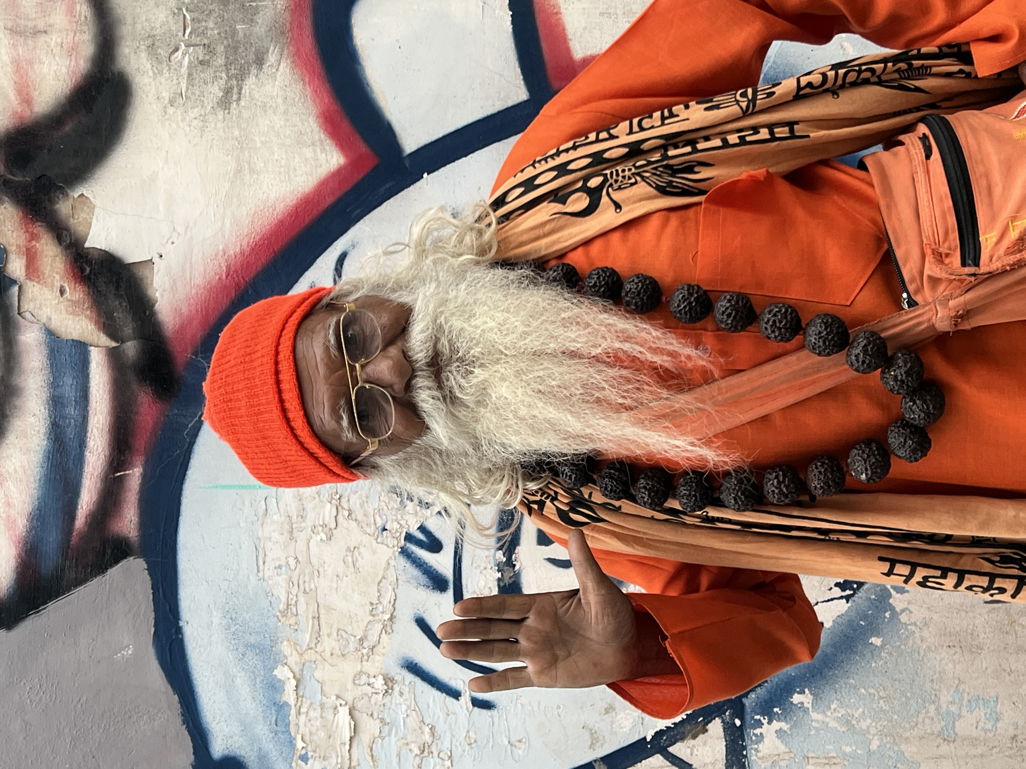 Orange-robed figure by a graffiti wall in Pushkar