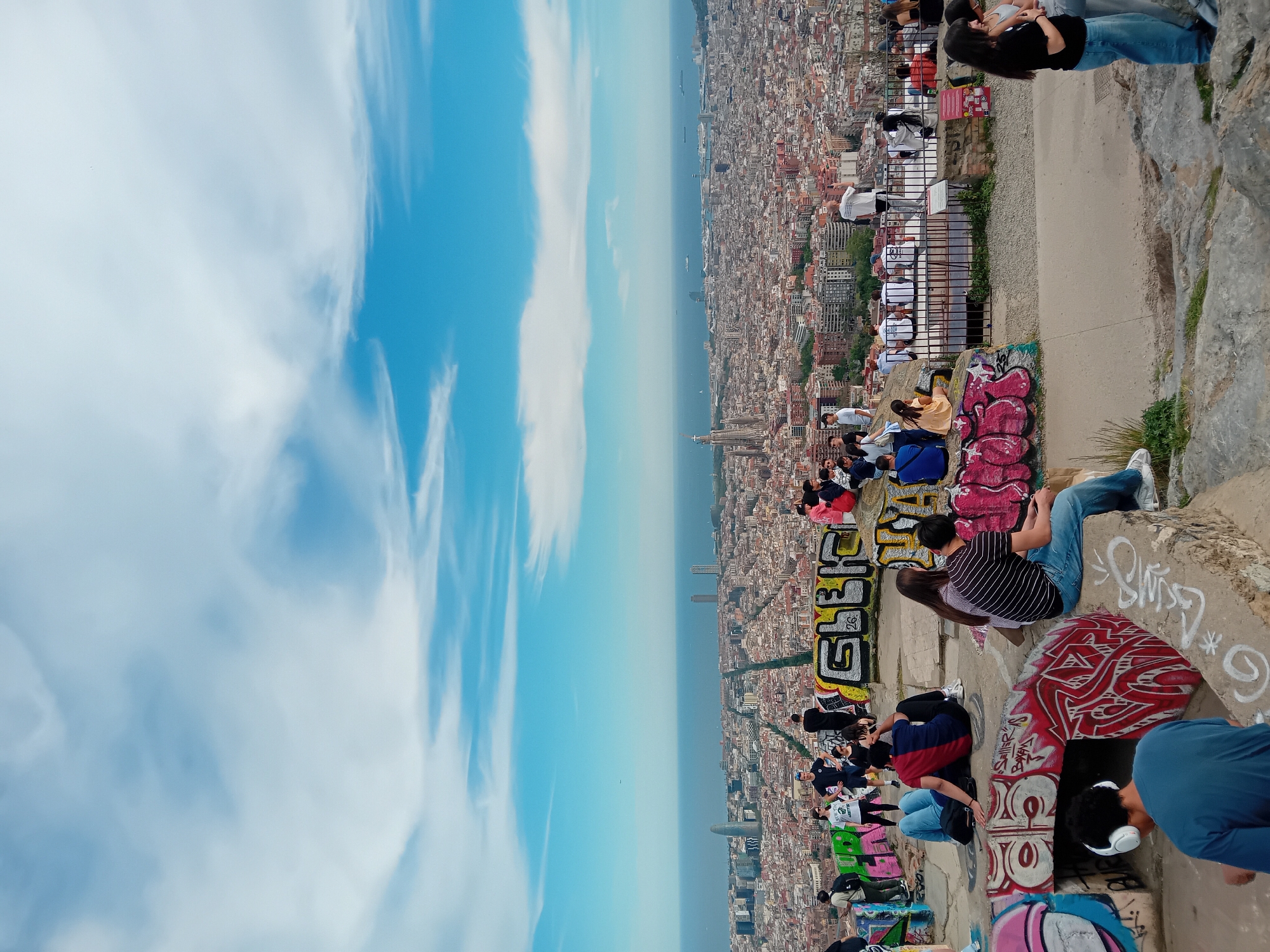 People gather on Barcelona overlook ledge facing Mediterranean Sea