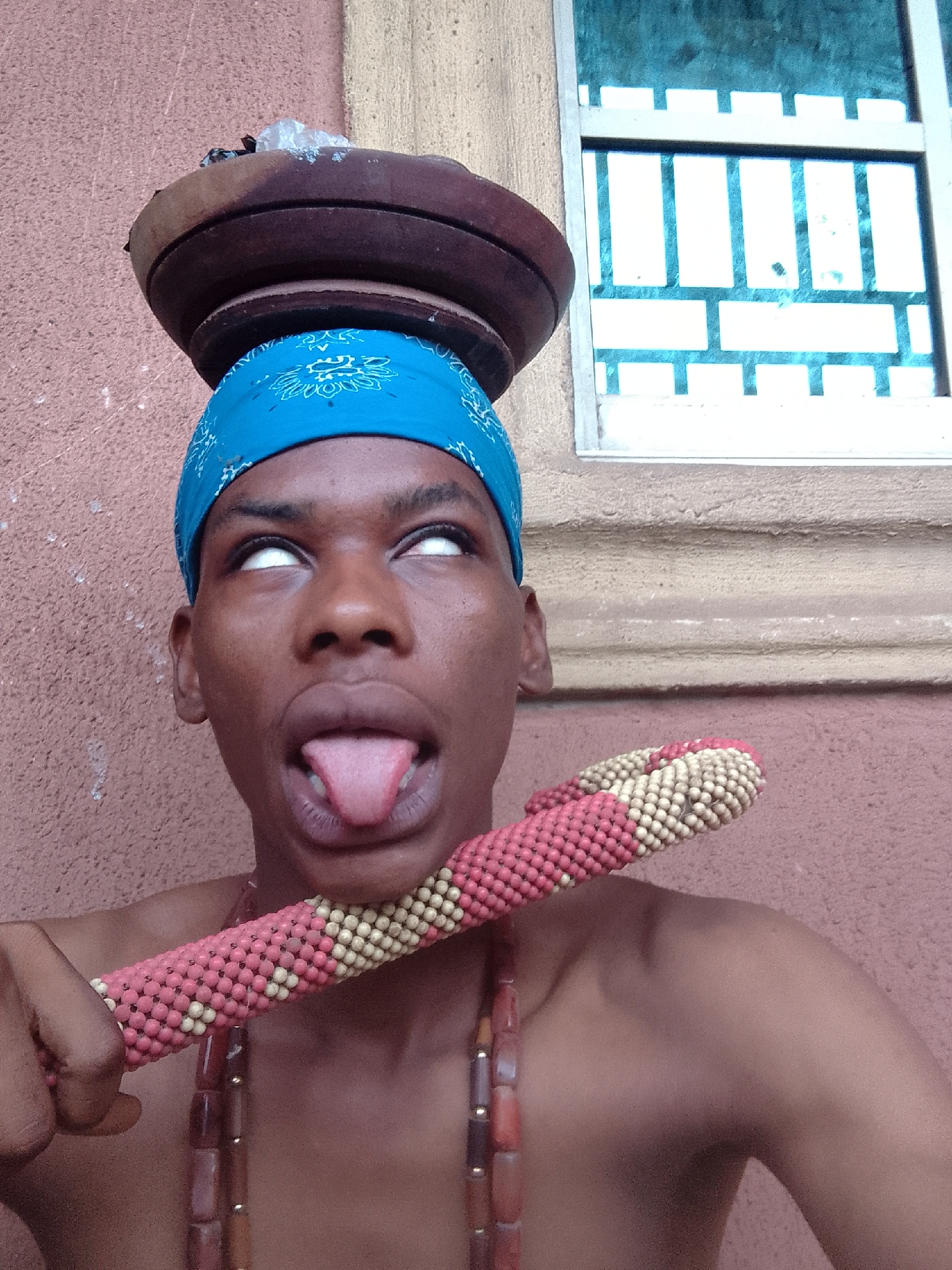 Person in blue bandana poses playfully with traditional artifacts