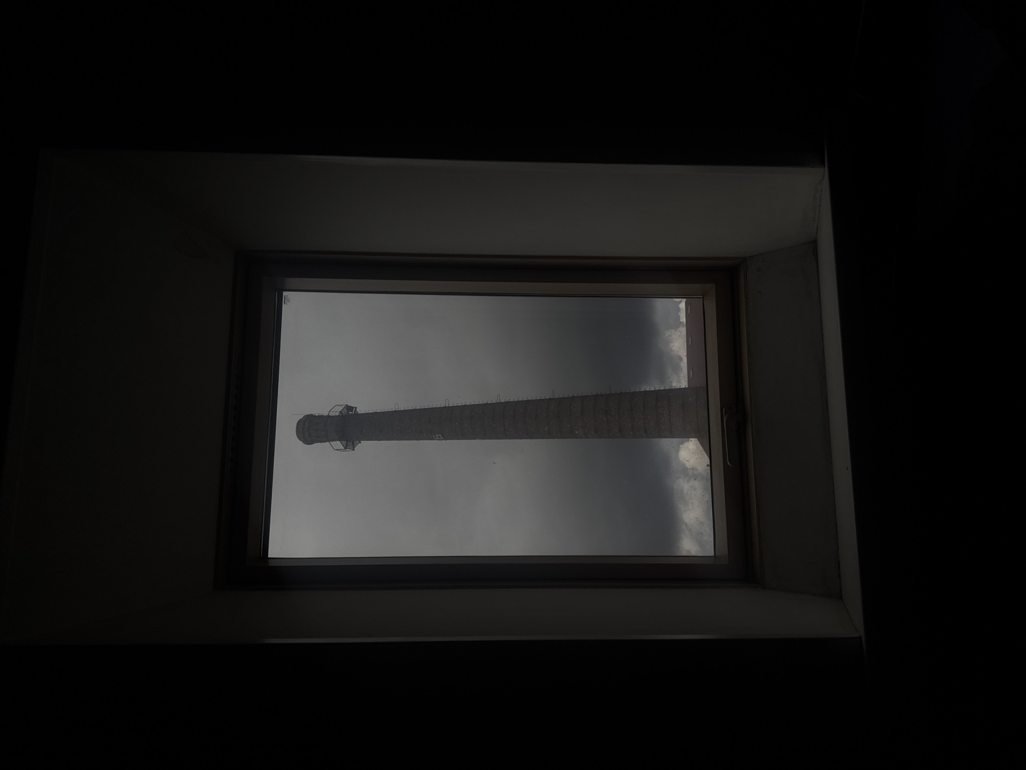 Brick chimney framed by a window under a brooding sky