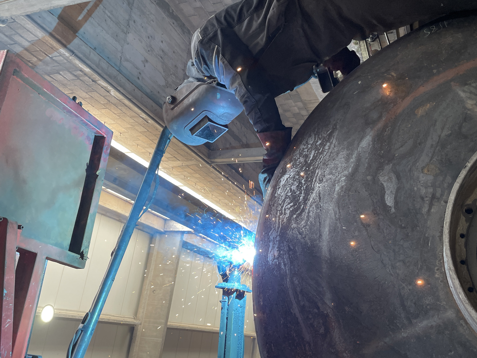 Welder works on metal object in Čeluga workshop