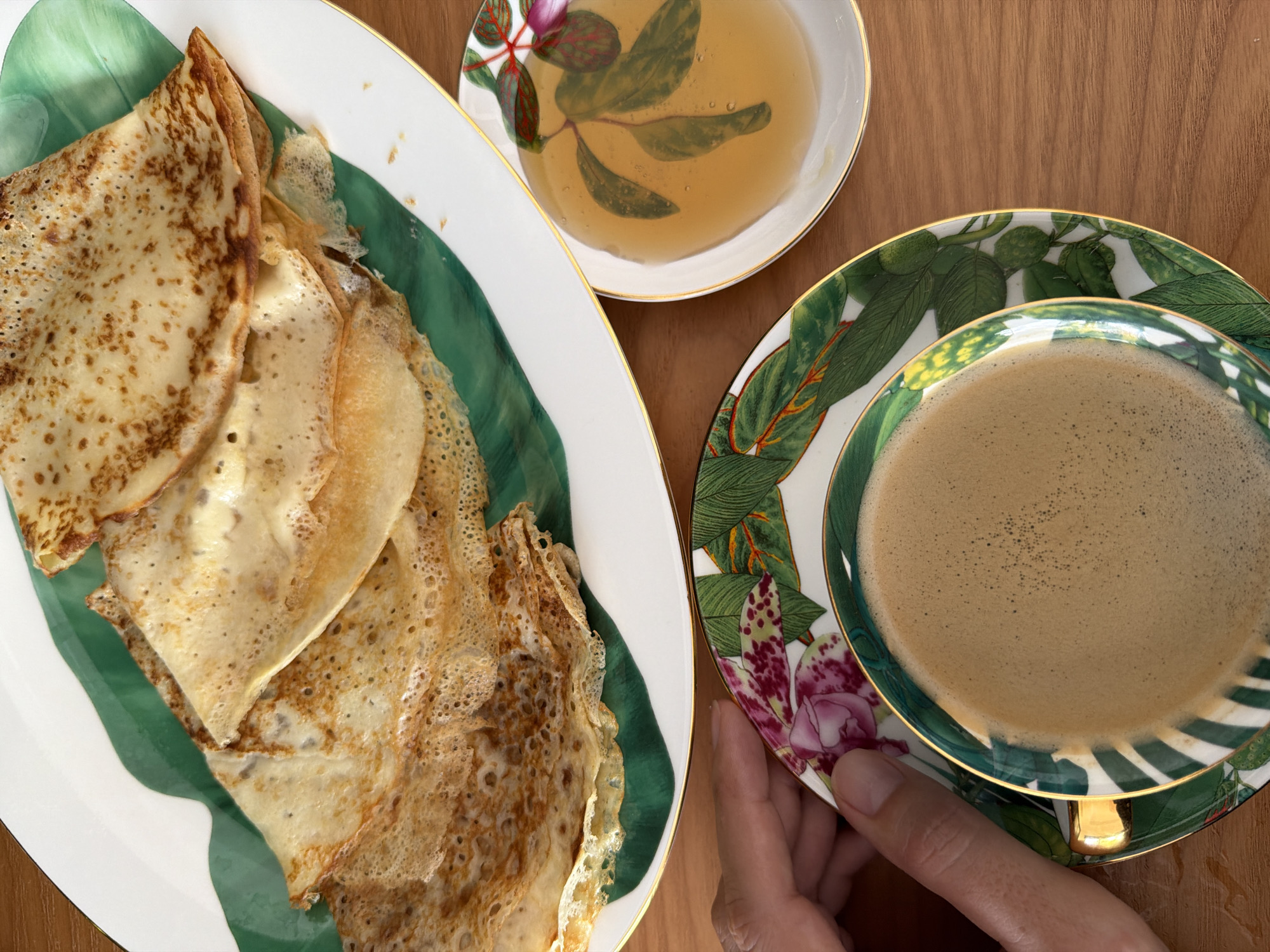 Crepes, coffee, and honey on a wooden breakfast table