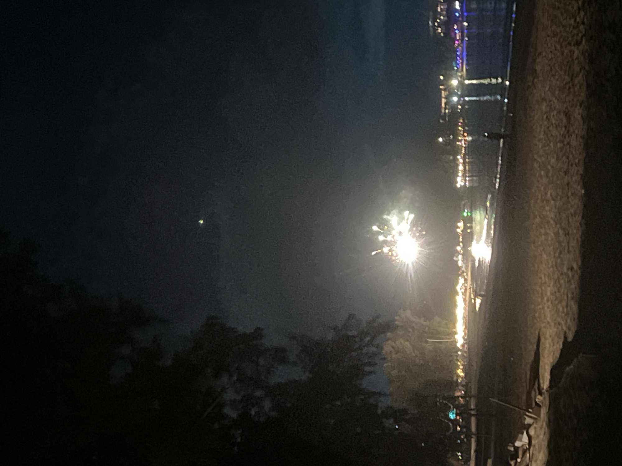 Beachside evening captured: stormy skies, fireworks, candlelit gathering