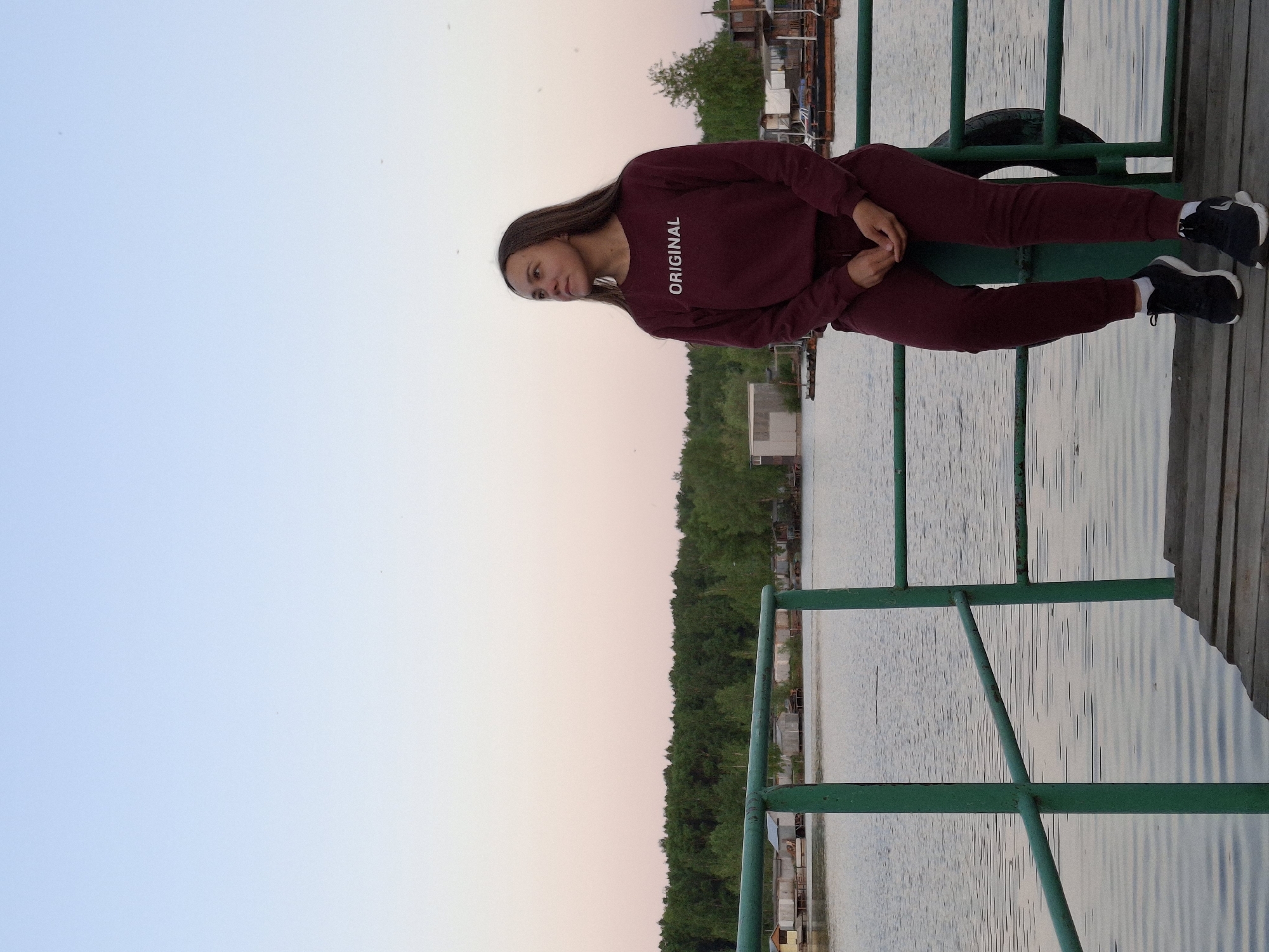 Woman sits on deck railing overlooking water in Chaikovsky