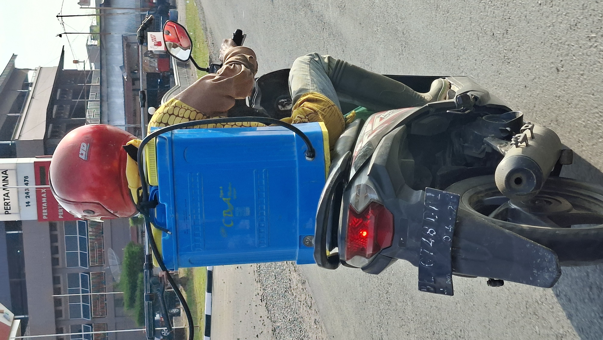 Motorcycle hauling a large blue container through Keudebayu