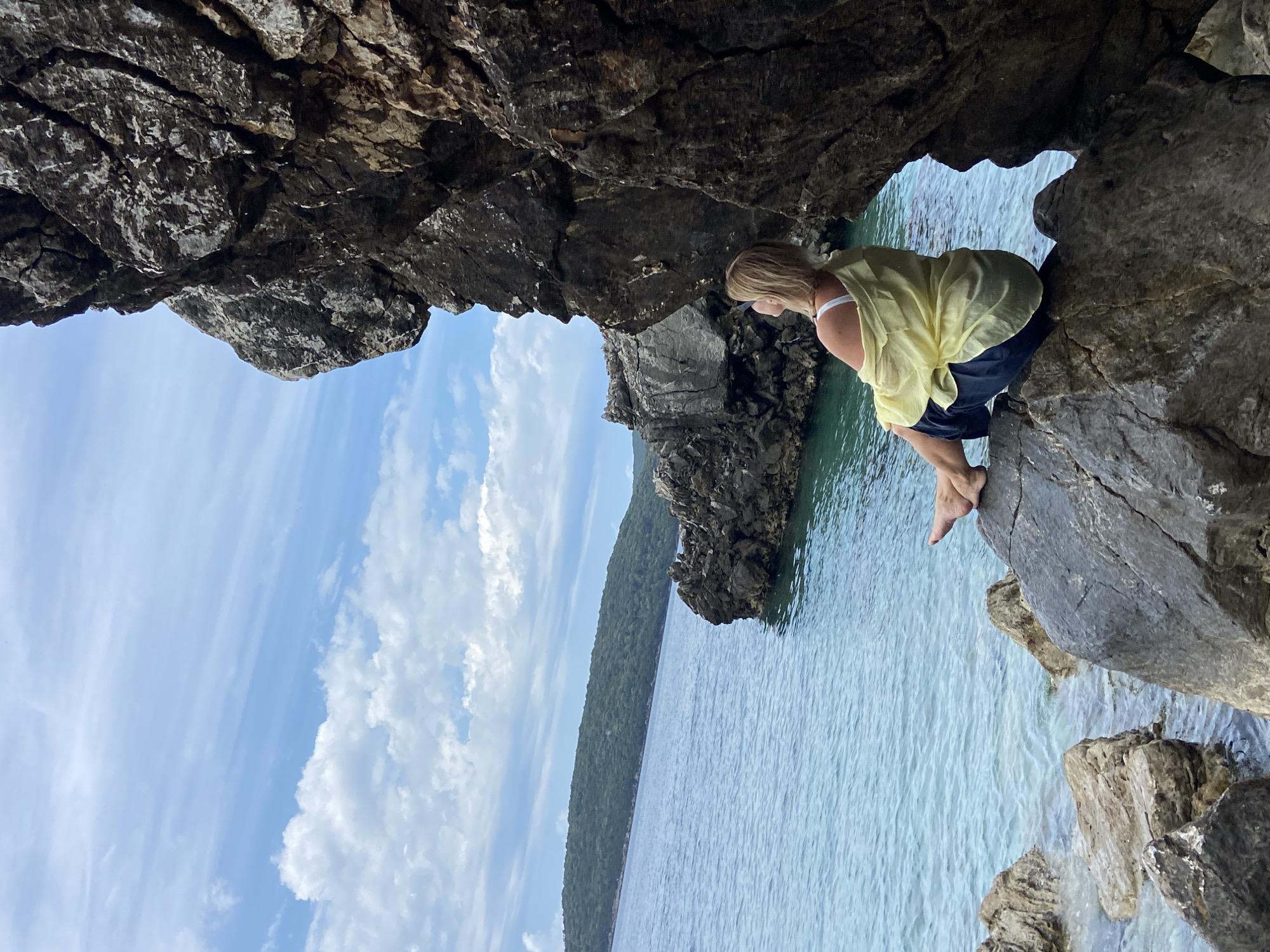 Woman sits on coastal rocks overlooking Adriatic in Montenegro