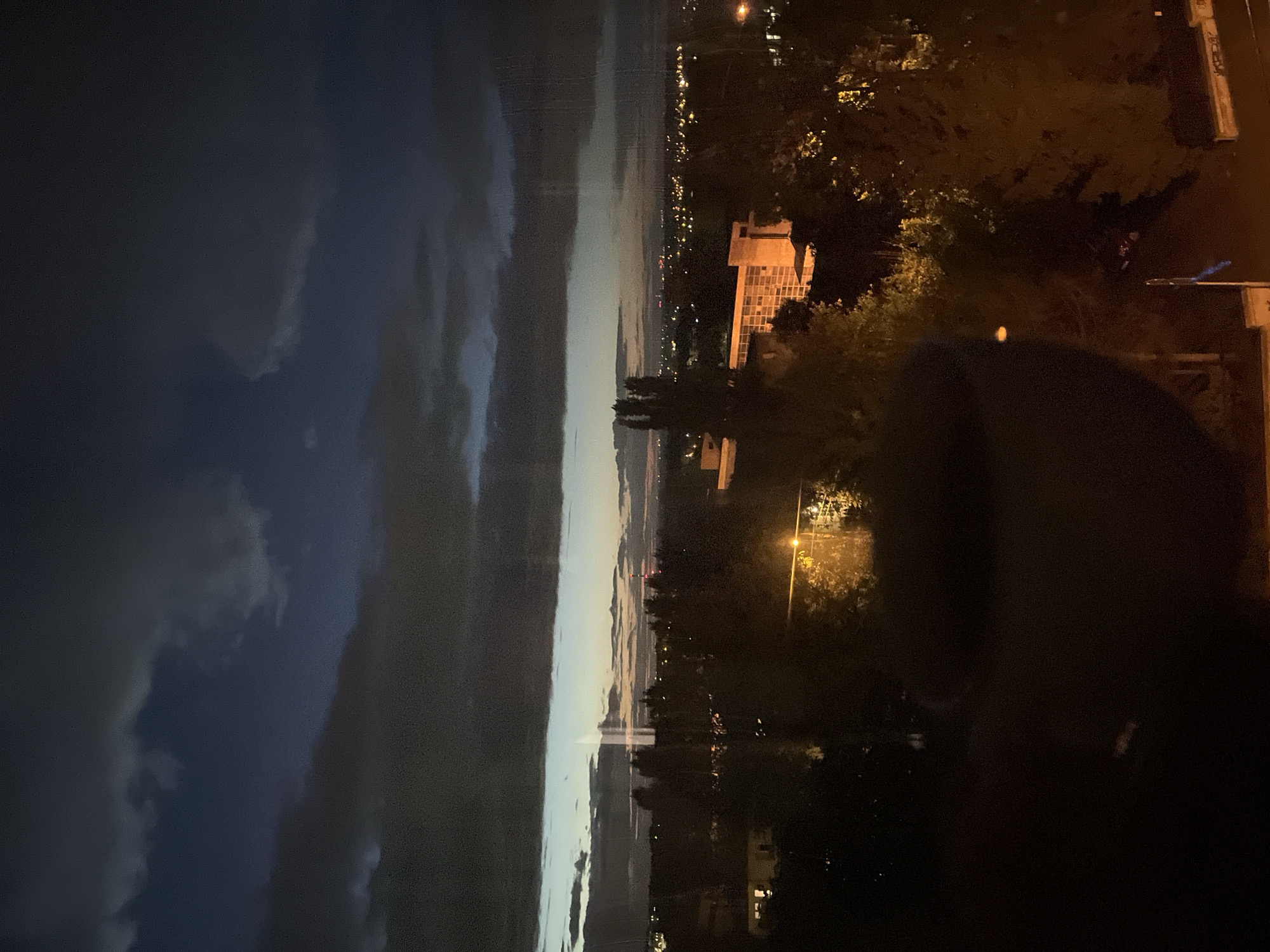 City skyline transitions from twilight to night under dramatic clouds