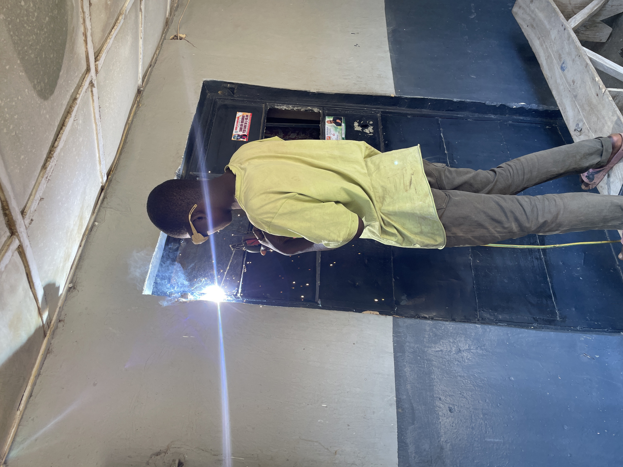 Welder works on metal frames in Jos, Nigeria morning