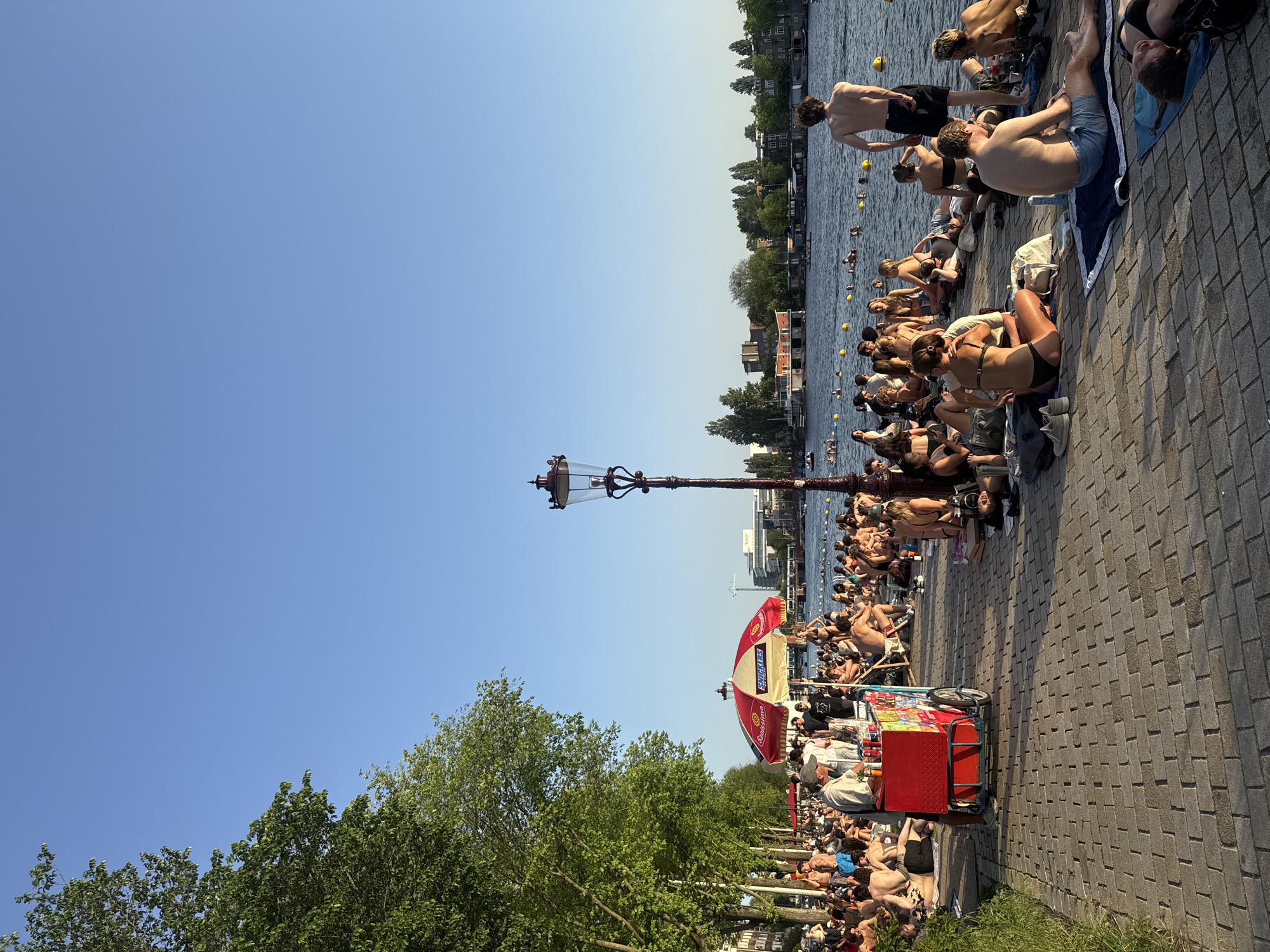 Amsterdam residents enjoy sunny evening swimming and sunbathing along canal