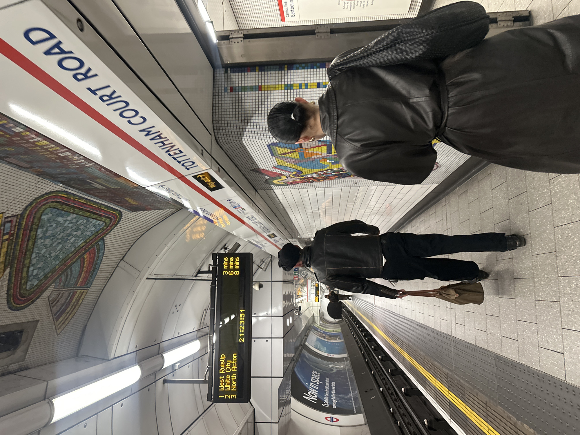 Woman takes selfie at London Underground station near beauty ads