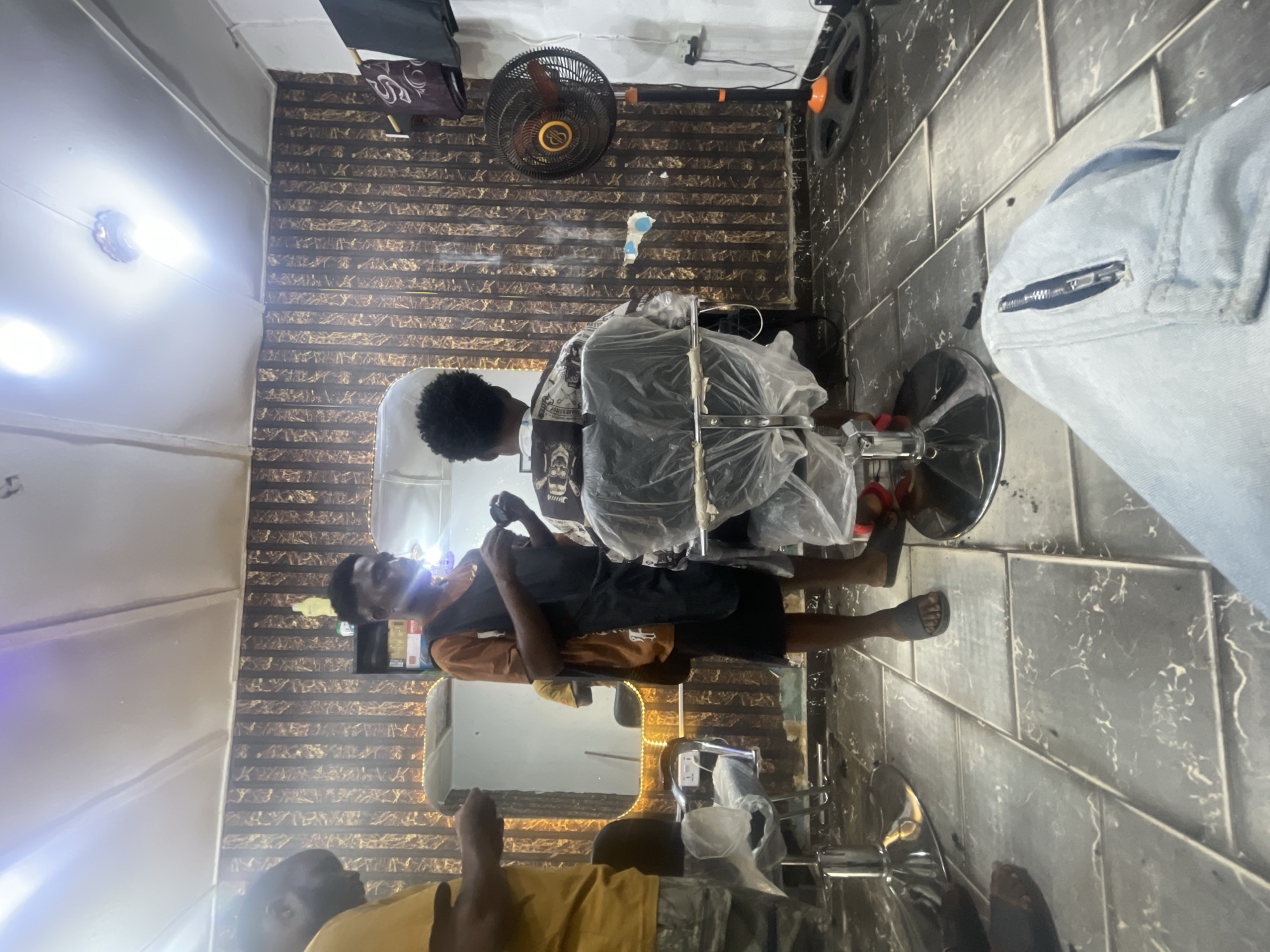Barber serves customer at Lokoja shop