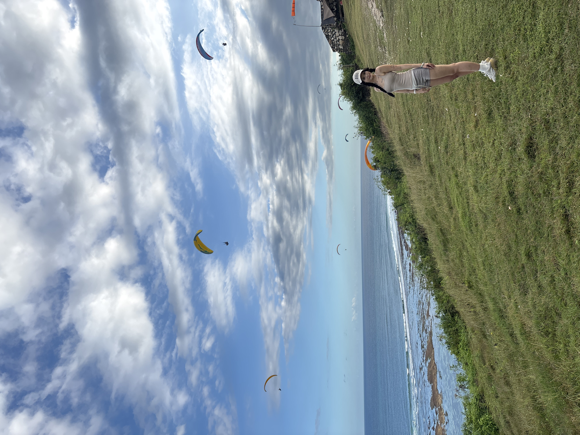 Paragliders soar over Kuta Selatan cliffs as tourists watch