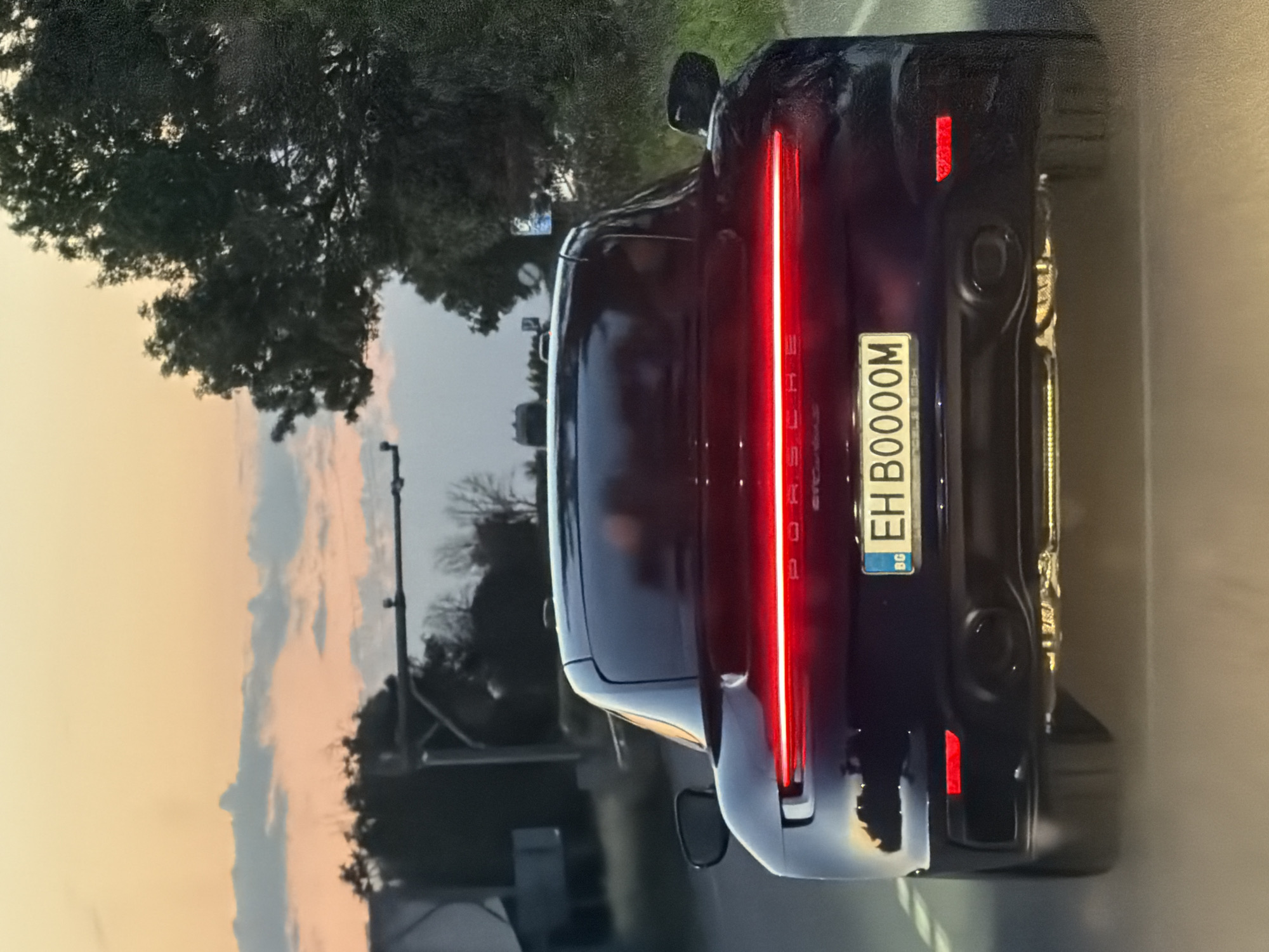 Dark blue Porsche rolling through rural Bulgaria, brake lights on
