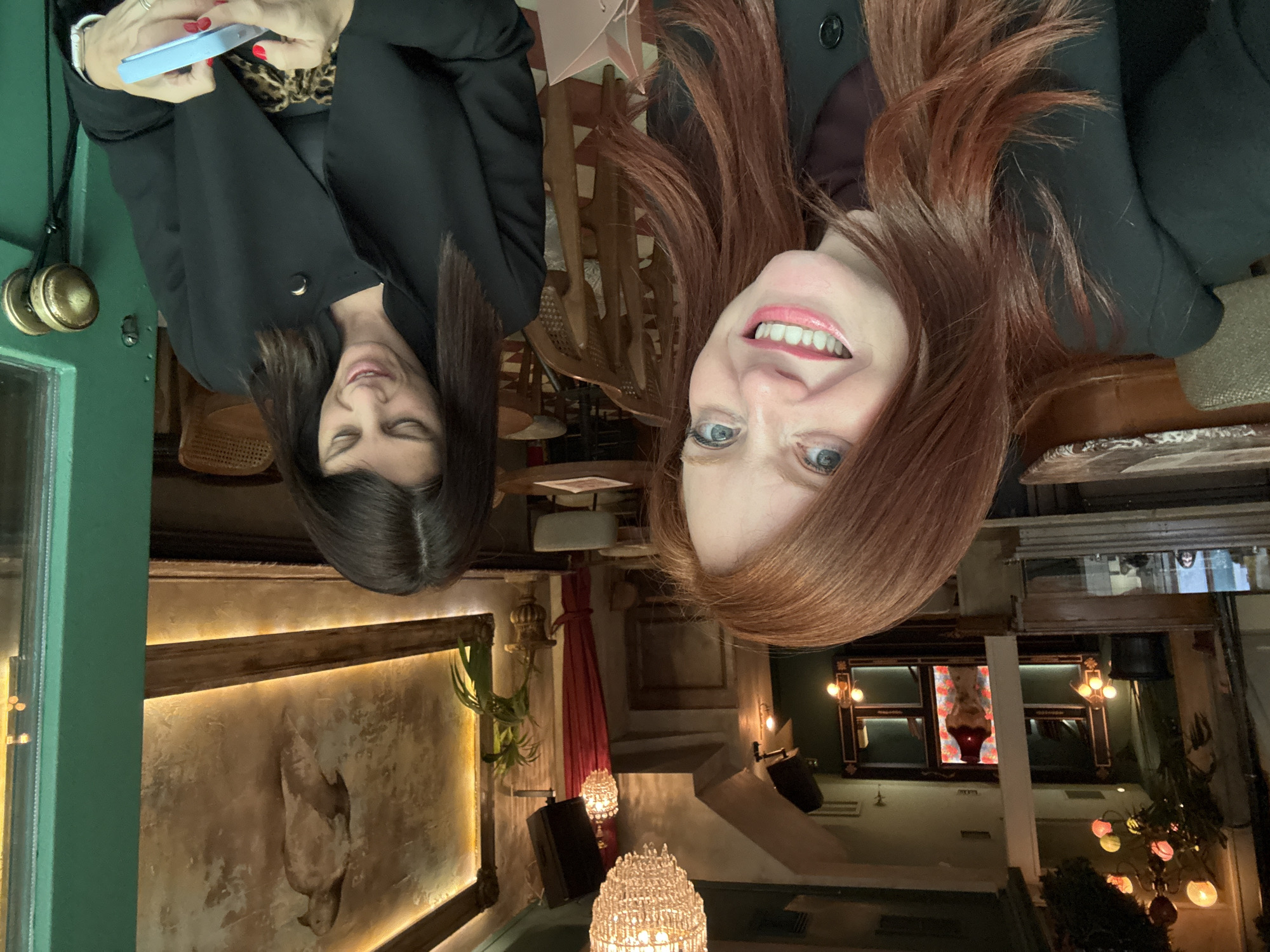 Two women photographed at Athens restaurant, one checking phone