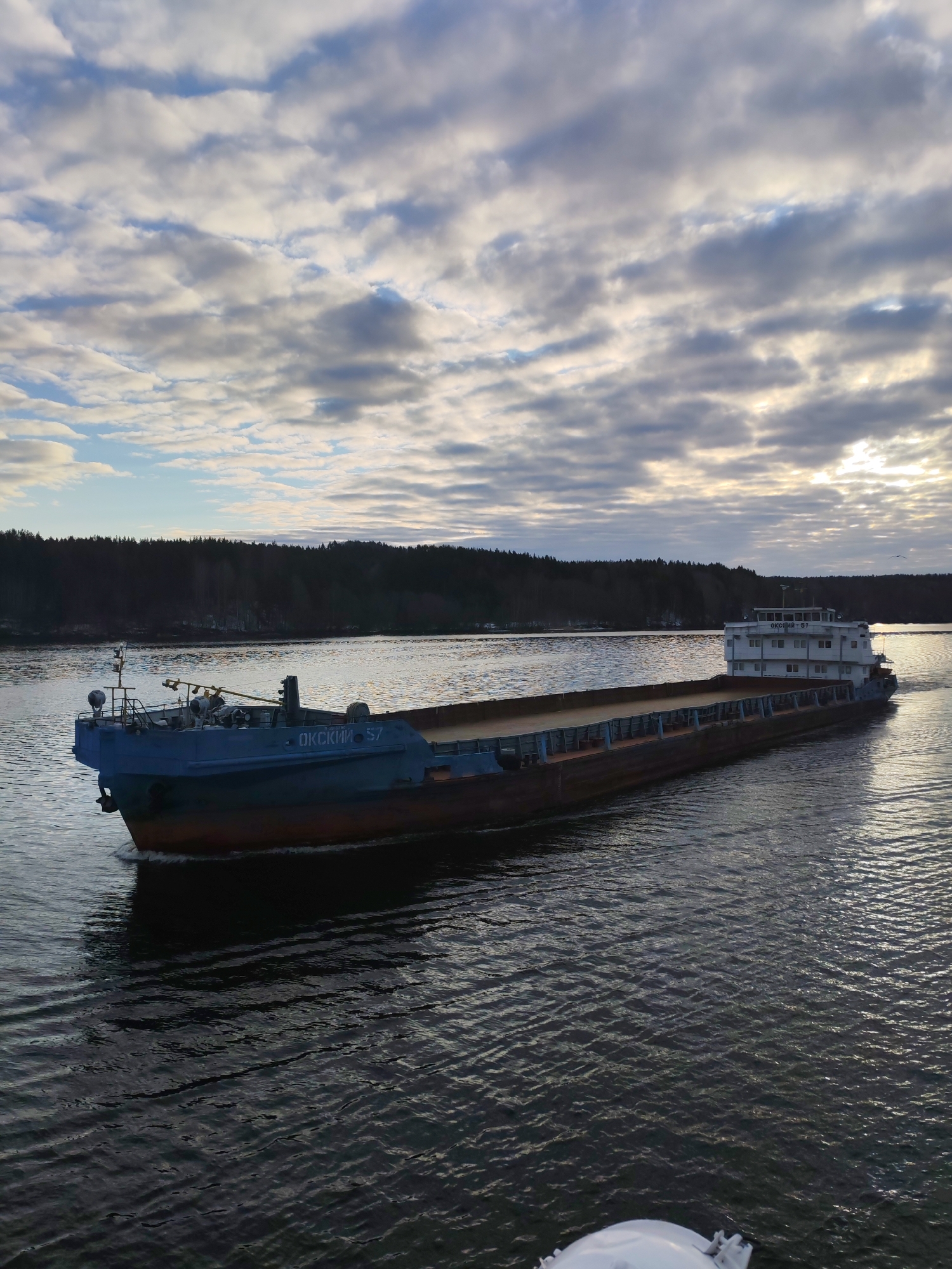 Barge transits Russian waterway near Ozerki under cloudy skies
