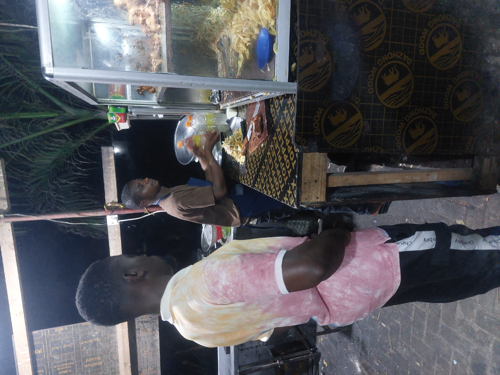 Street vendor prepares food at nighttime stall in Dar es-Salaam