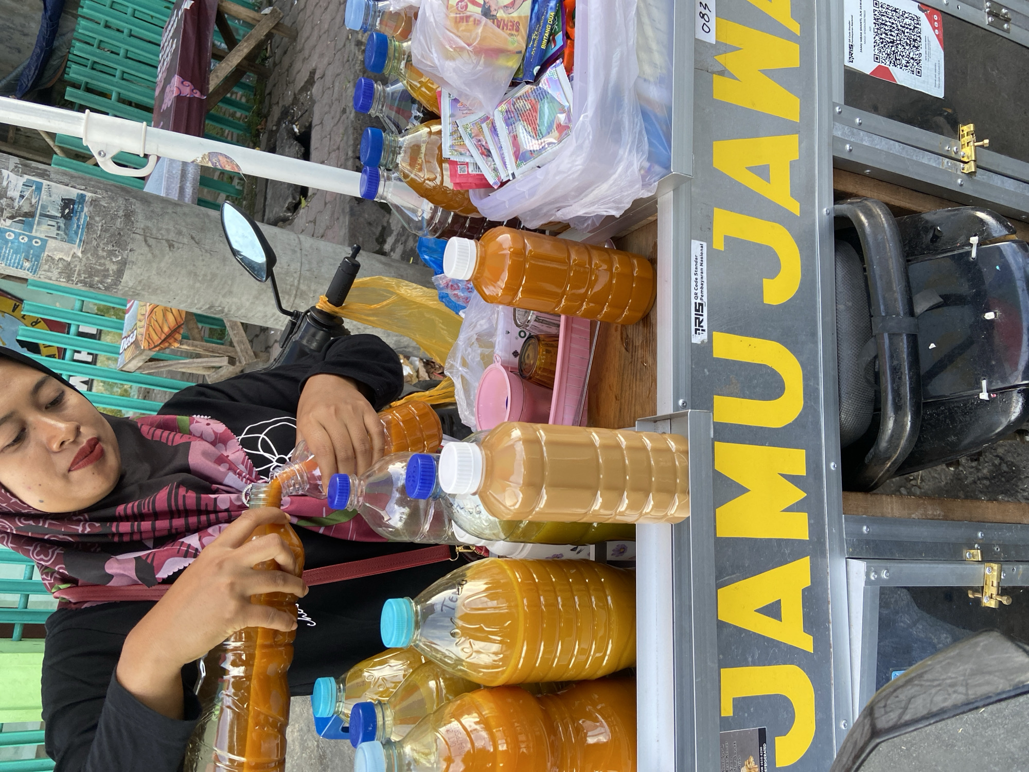 Beverage vendor serves customers from cart in Sumbersari