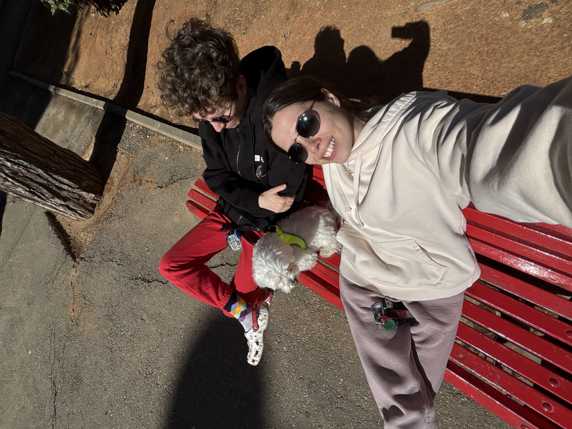 Two people, dog rest on park bench in Bat Yam