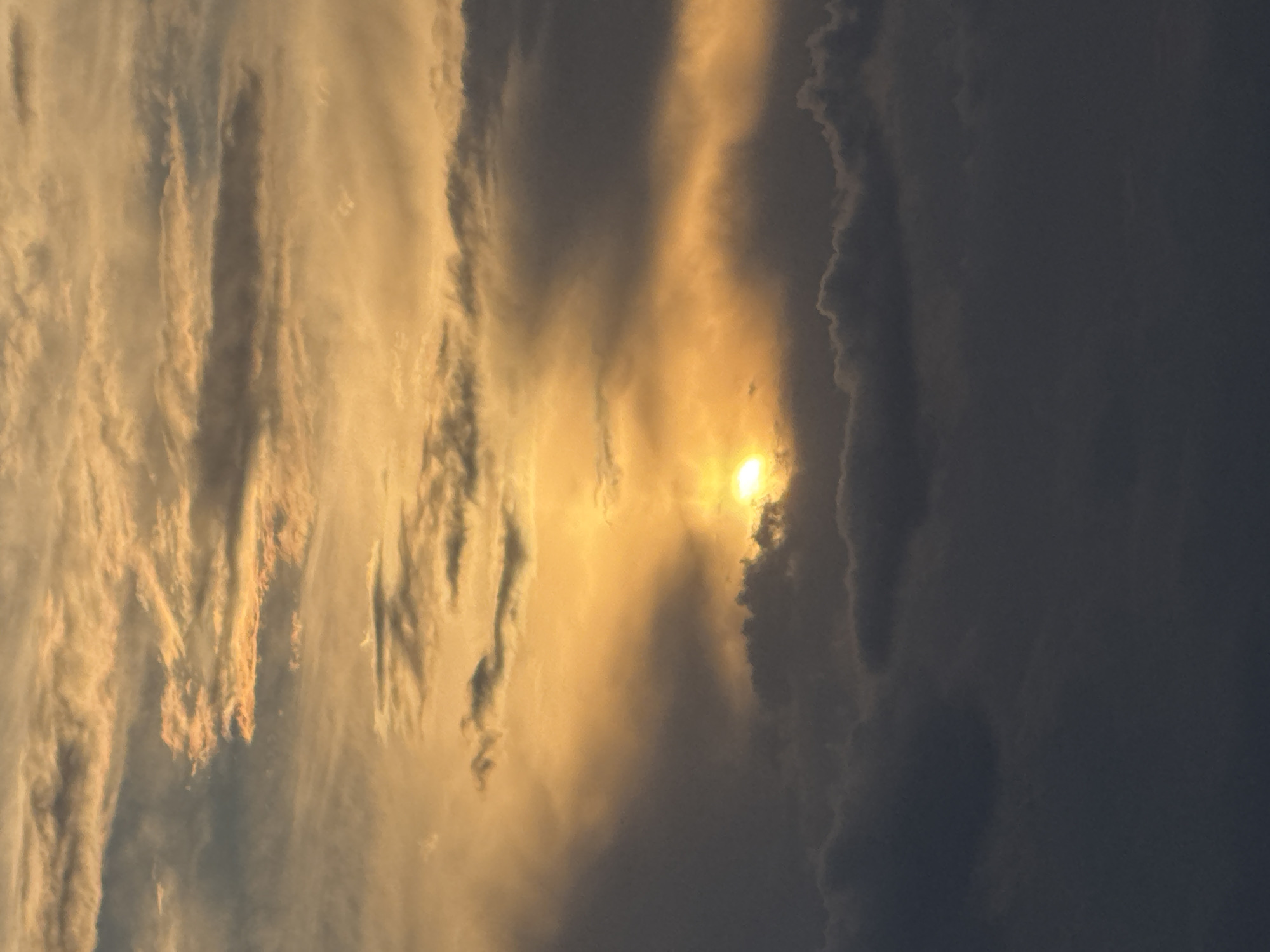 Golden sunset breaks through heavy clouds over a city