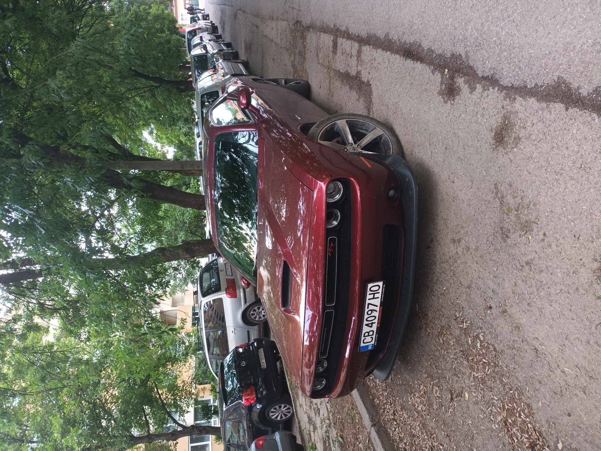 Woman reclines on Dodge Challenger hood in city street