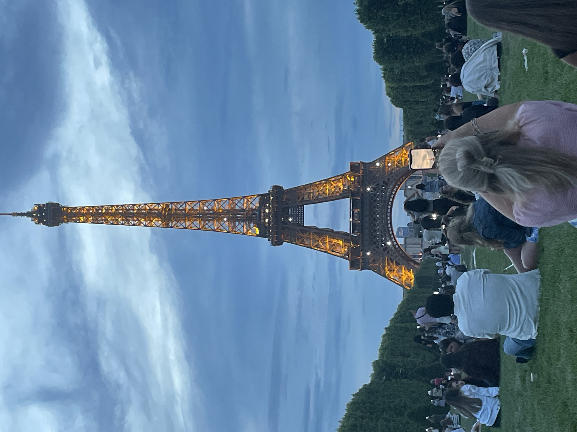 Evening crowd gathers at illuminated Eiffel Tower in Paris