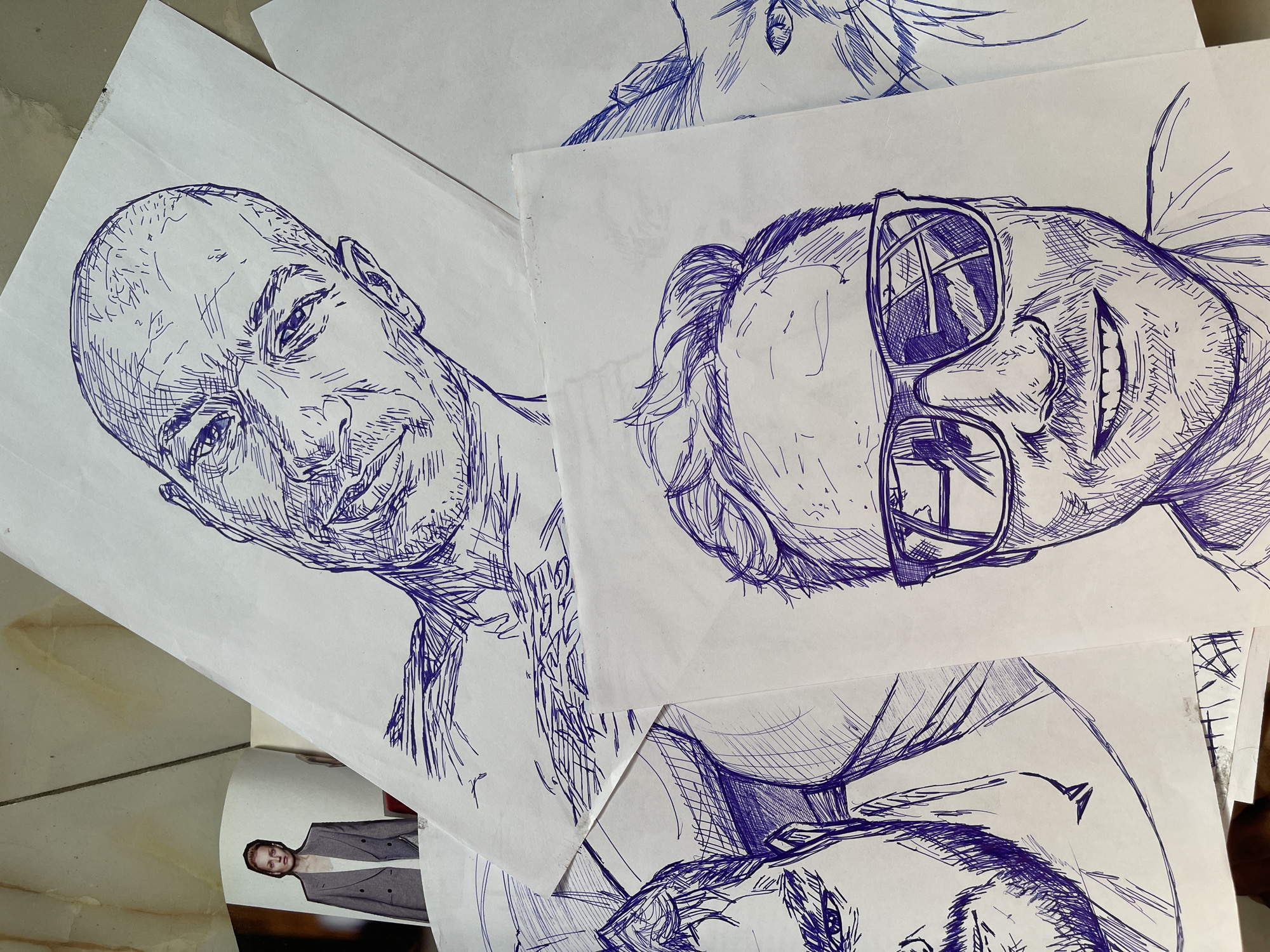 Pen-and-ink portrait sketches arranged on a surface in Abuja