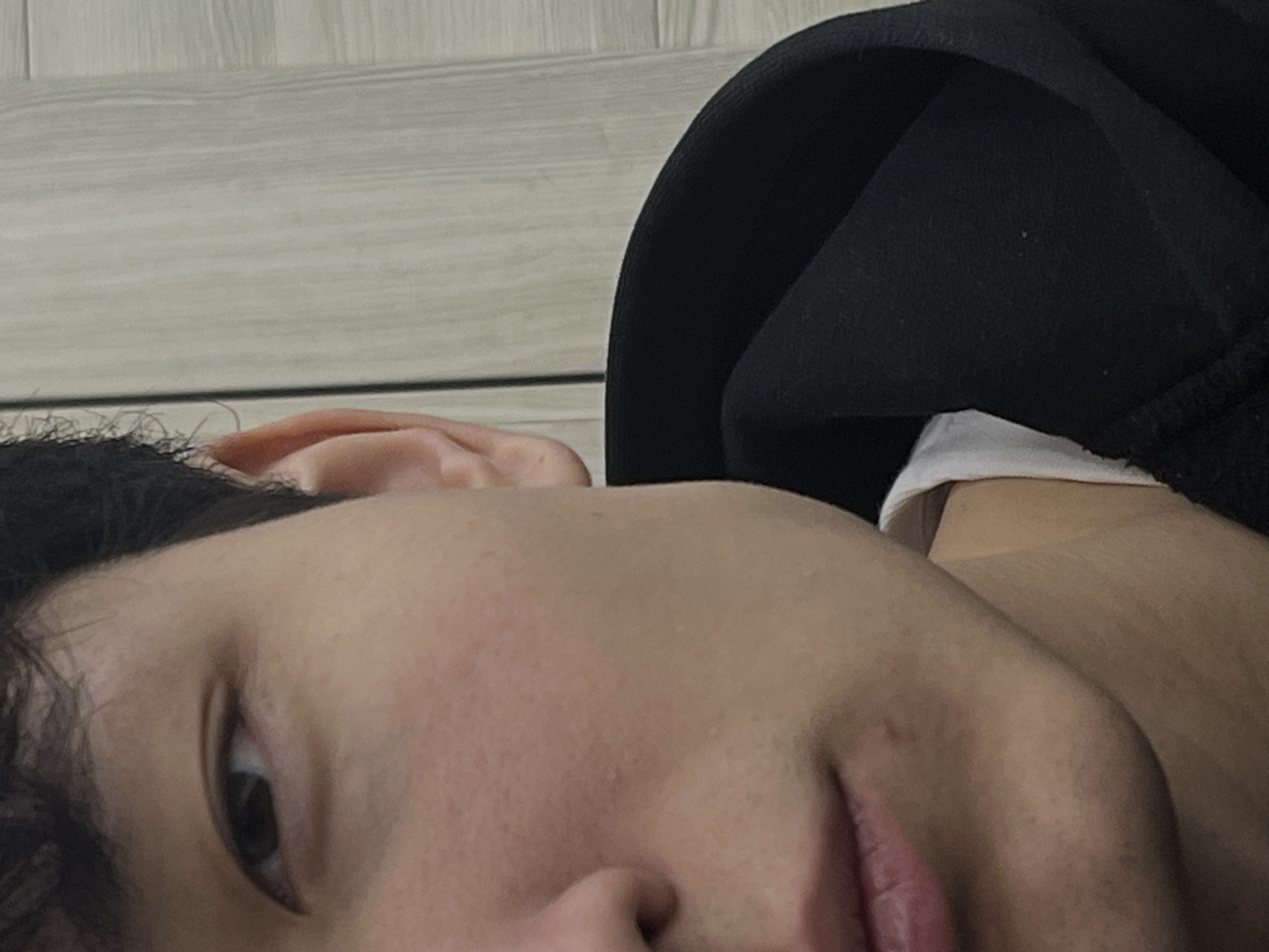 Person in black hoodie uses smartphone indoors during evening
