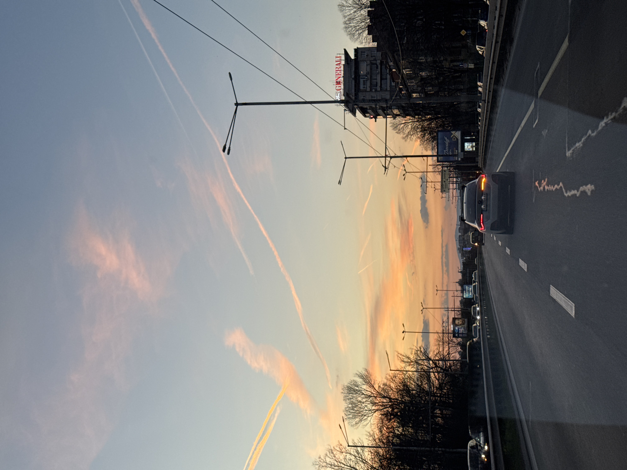 Dusk streetscape documented in Sofia with contrails overhead