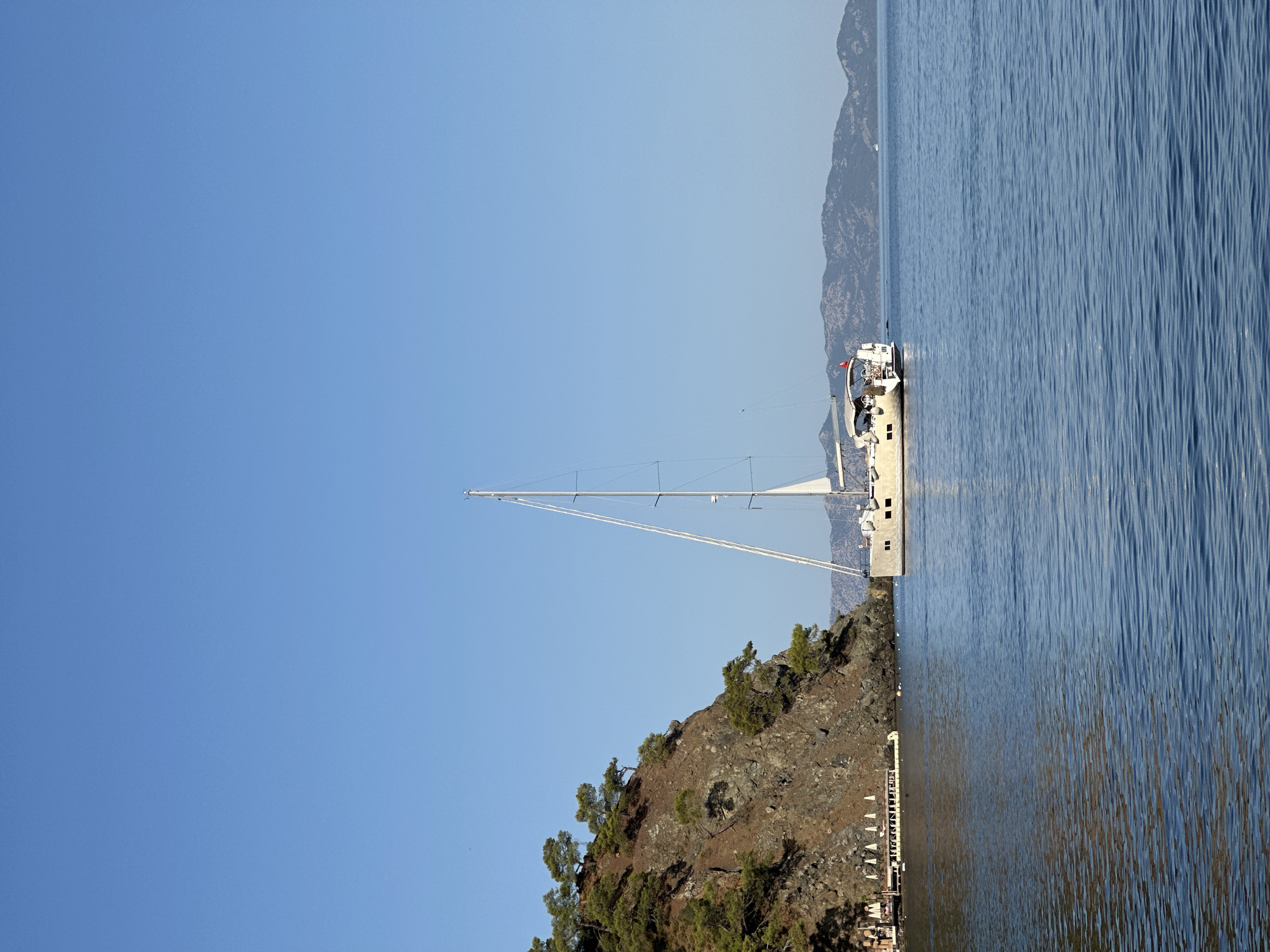 Sailboat anchored off Fethiye's rocky coastline on a clear morning