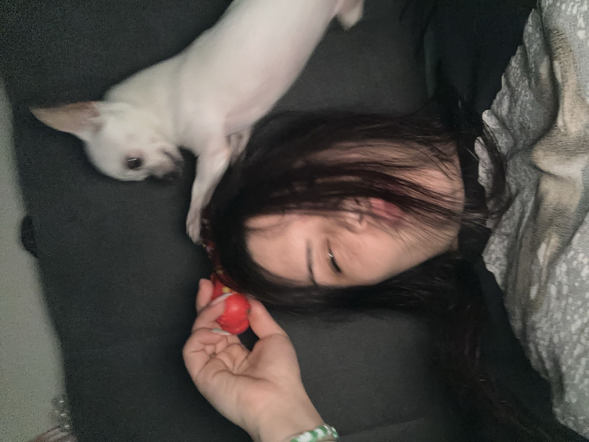 Woman rests with small dog on sofa in Sliven