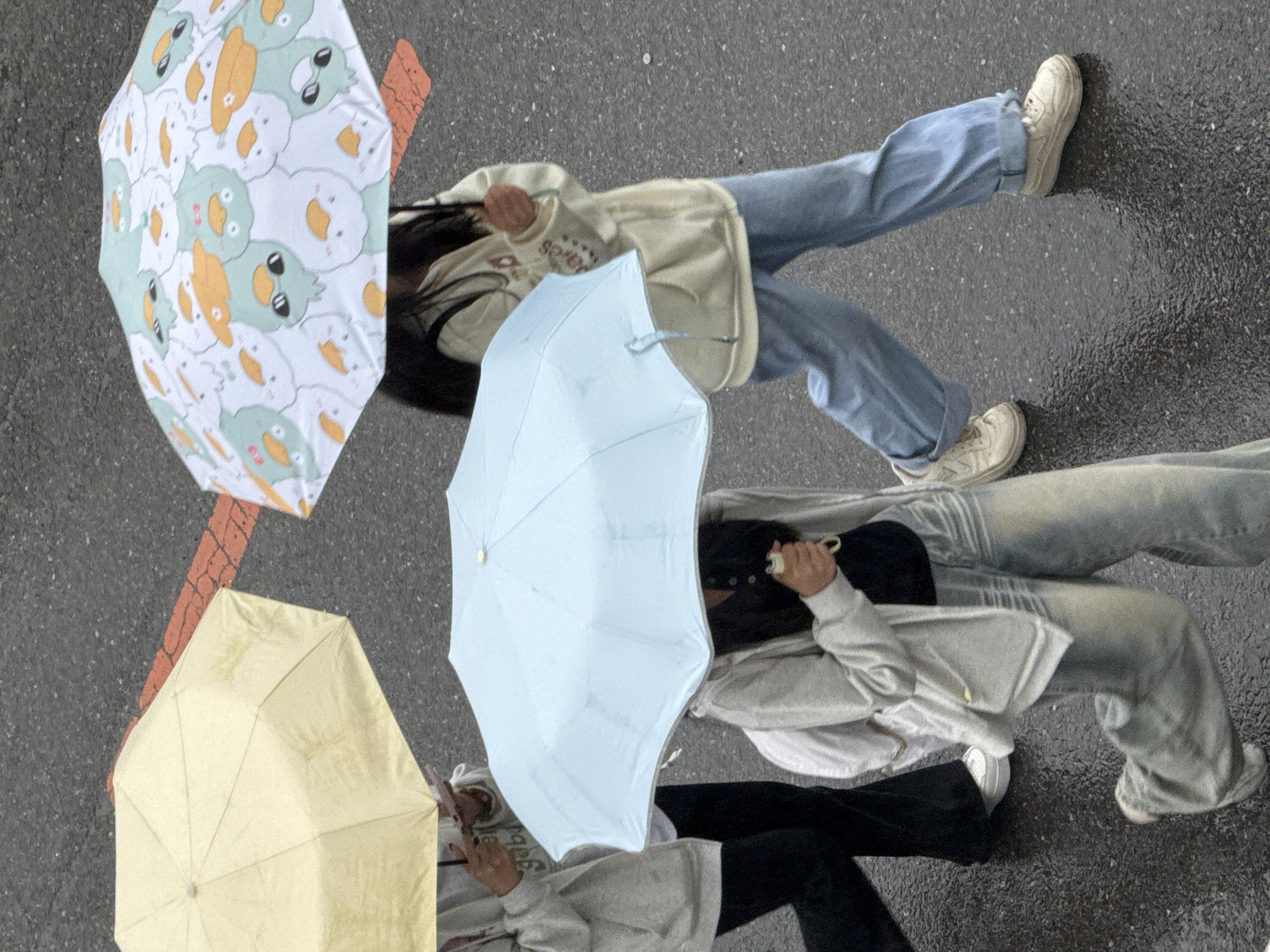 Pedestrians navigate rainy streets with umbrellas in Zhongtun, China