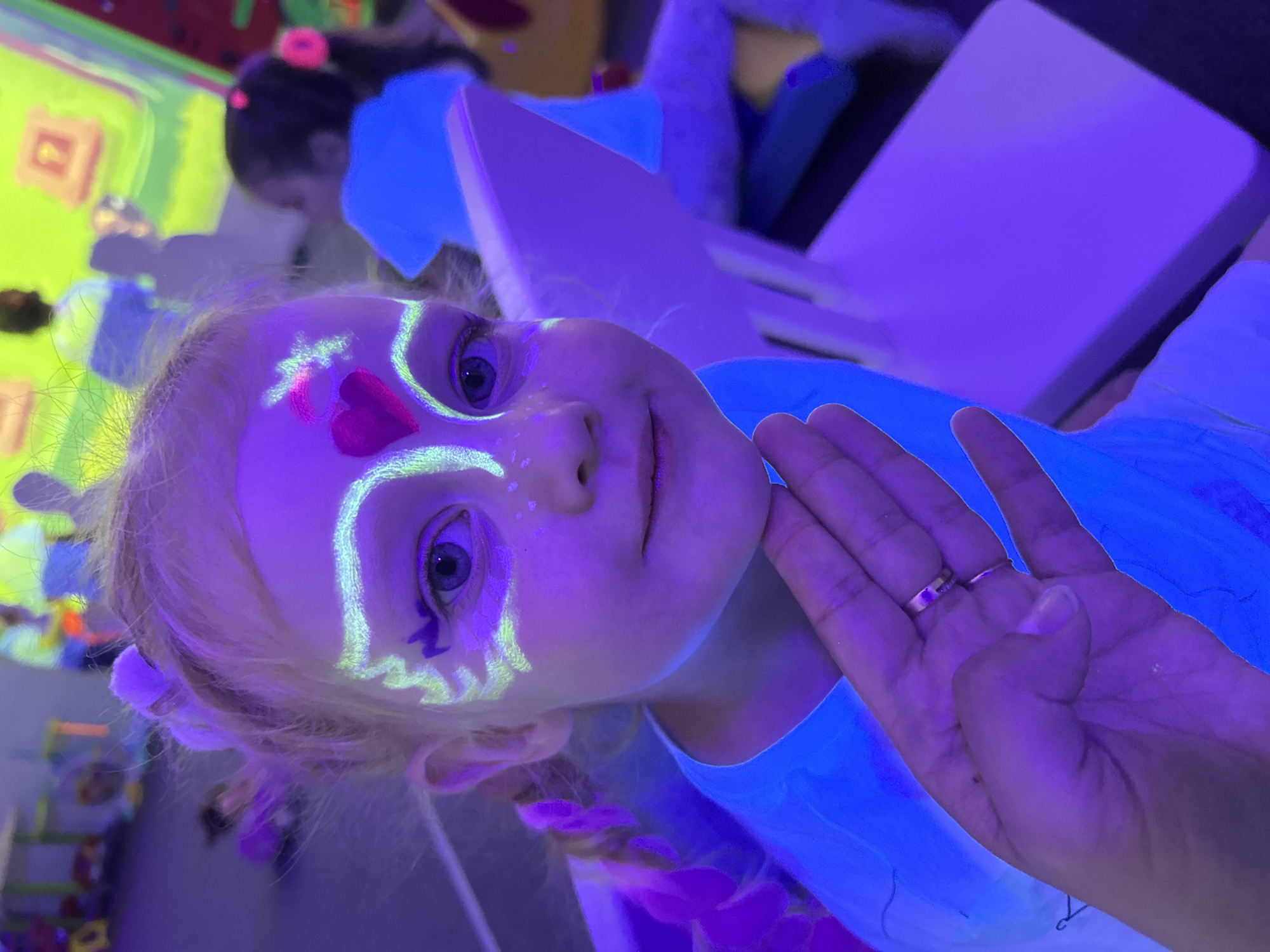 Glow-lit indoor kids' party with face paint, VR, and games