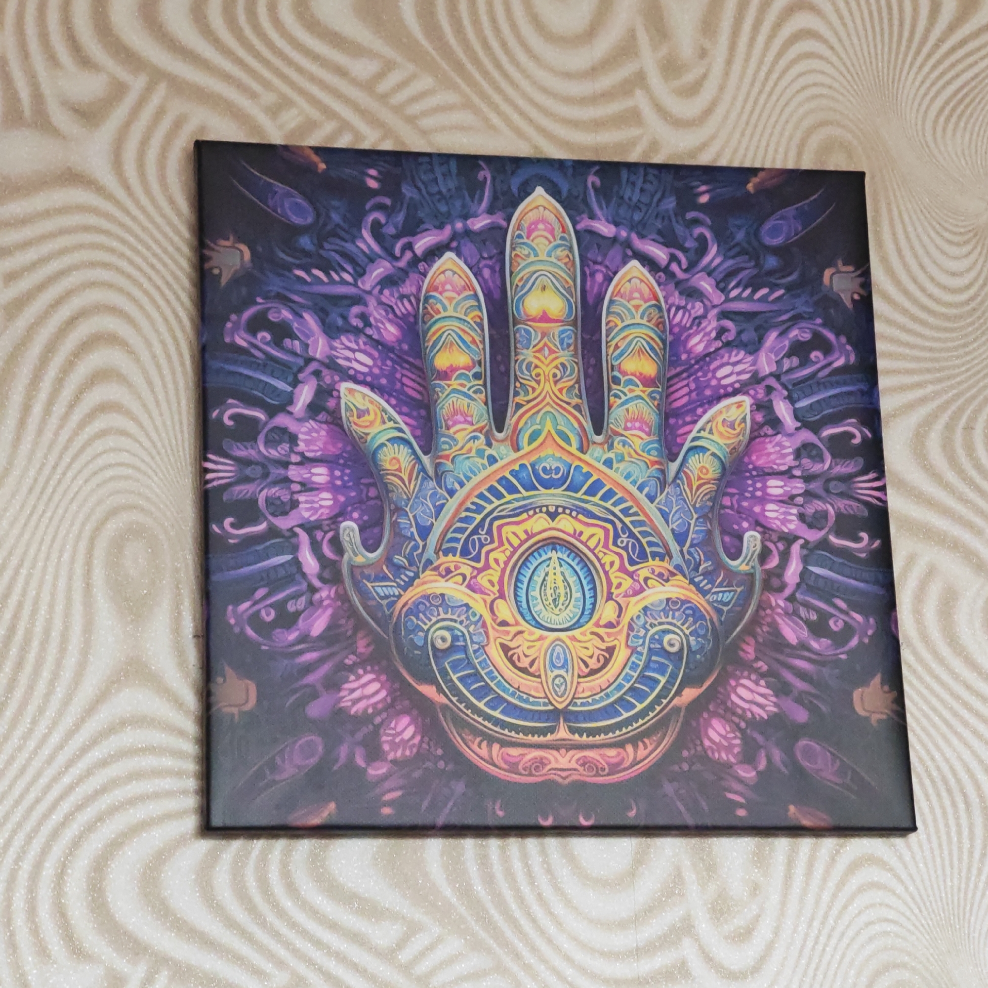 Canvas artwork featuring hand with eye symbol observed on wall