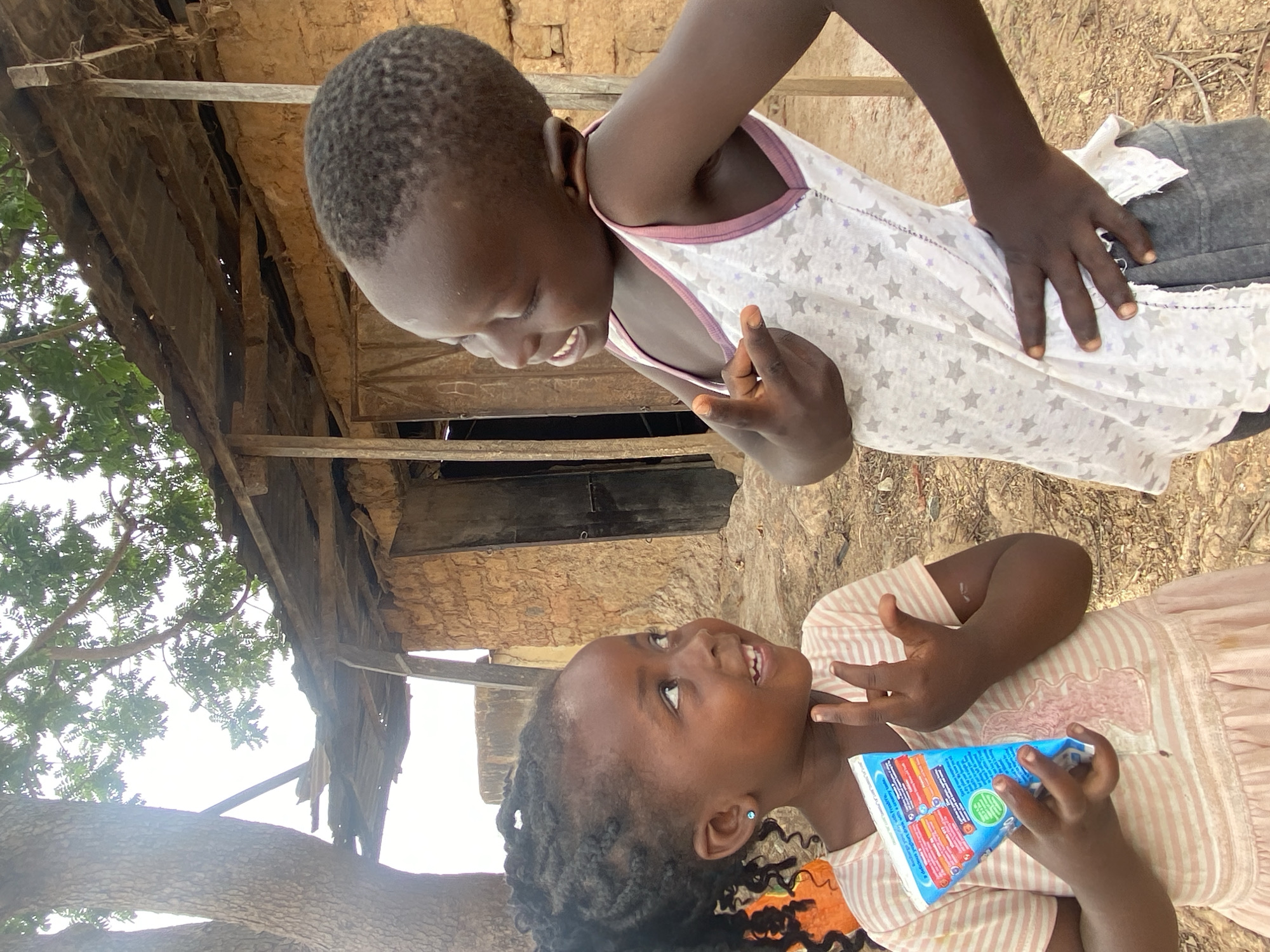 Two girls share juice boxes in Kuru Dungus, Nigeria