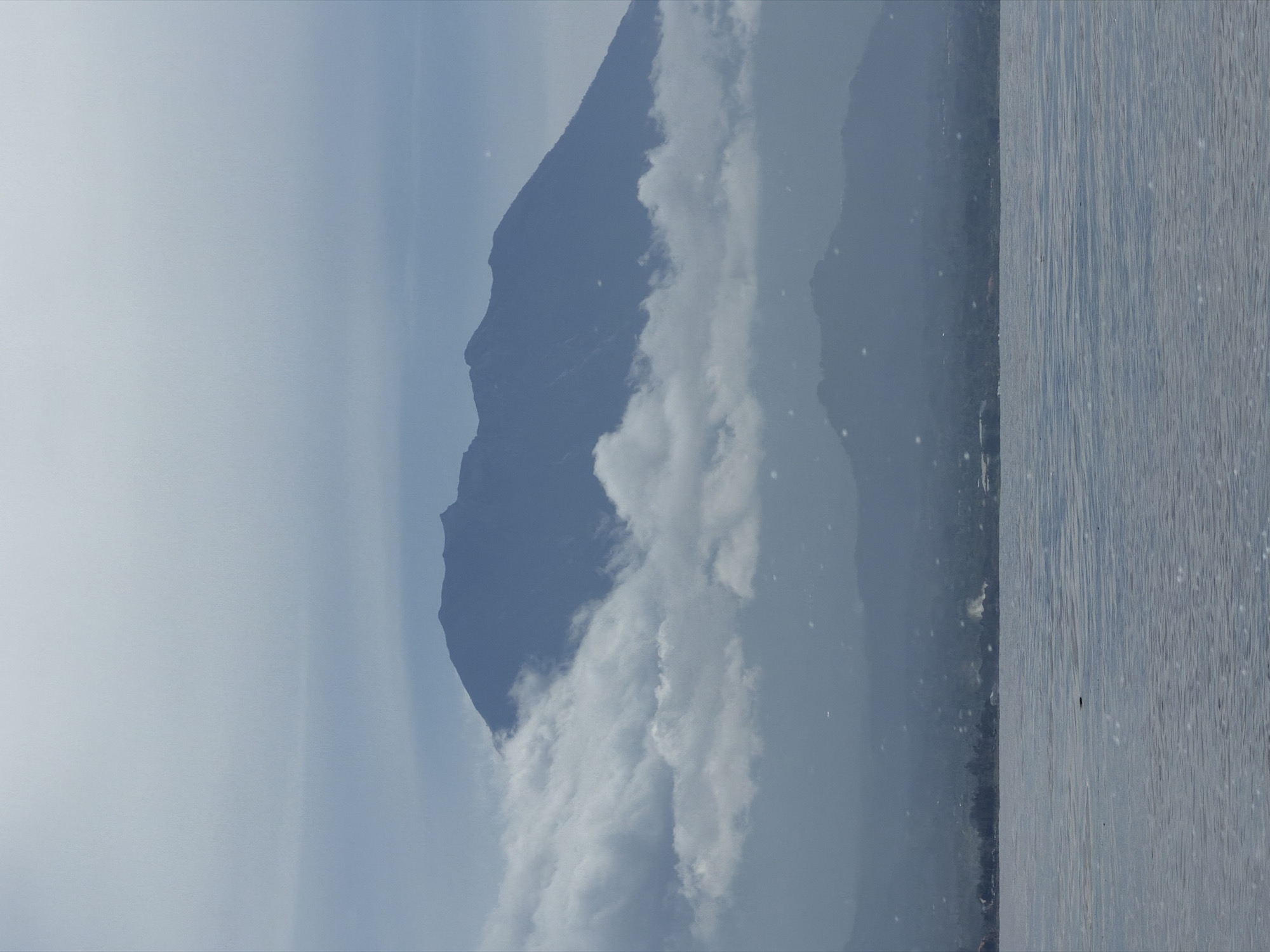 Clouded mountain observed across calm Indonesian waters early morning
