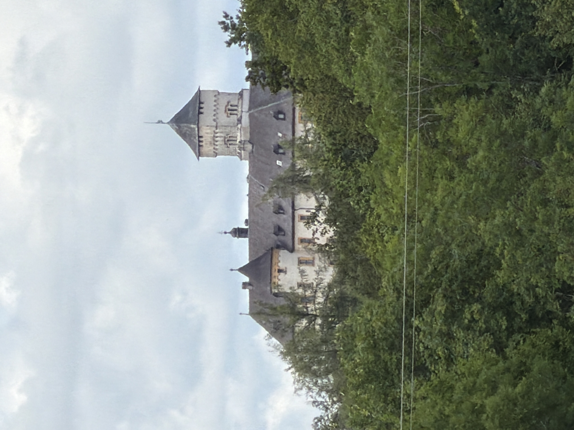 Hilltop castle peeks through summer trees in northern Bavaria