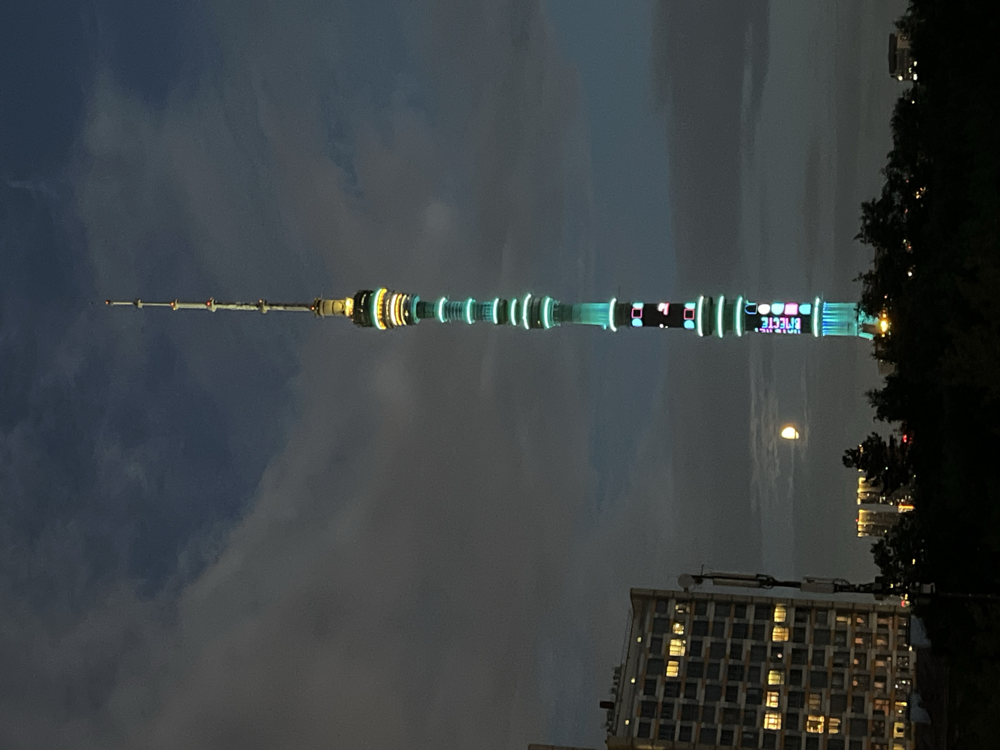 Ostankino Tower glowing with colorful lights on a cloudy night