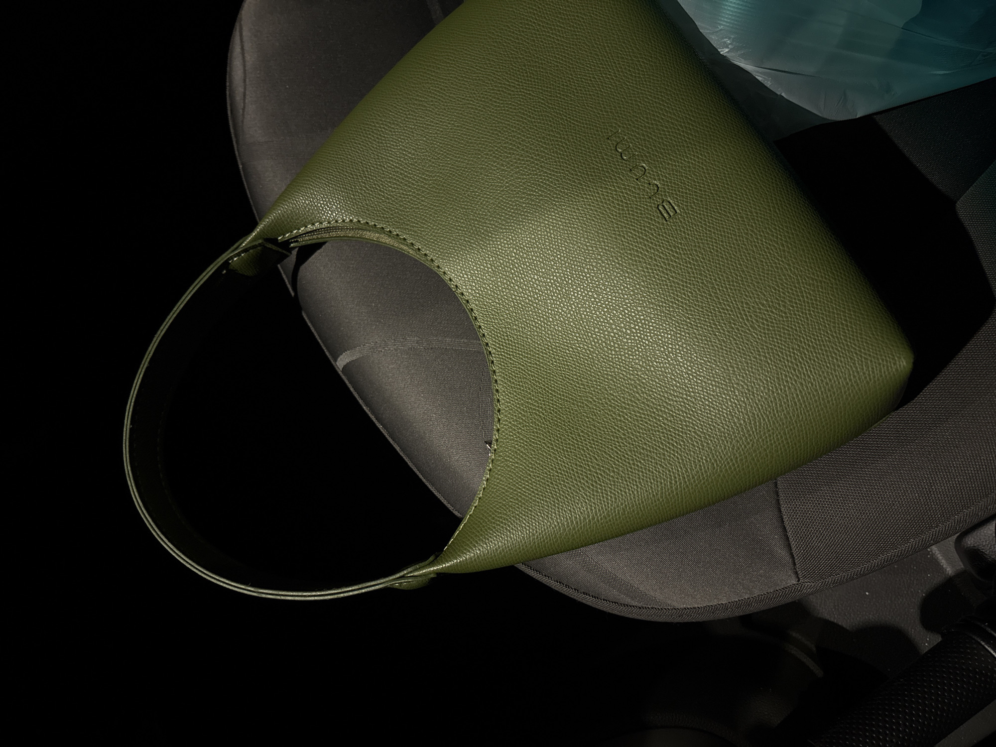 Olive green handbag photographed on car seat in Ust-Ilimsk