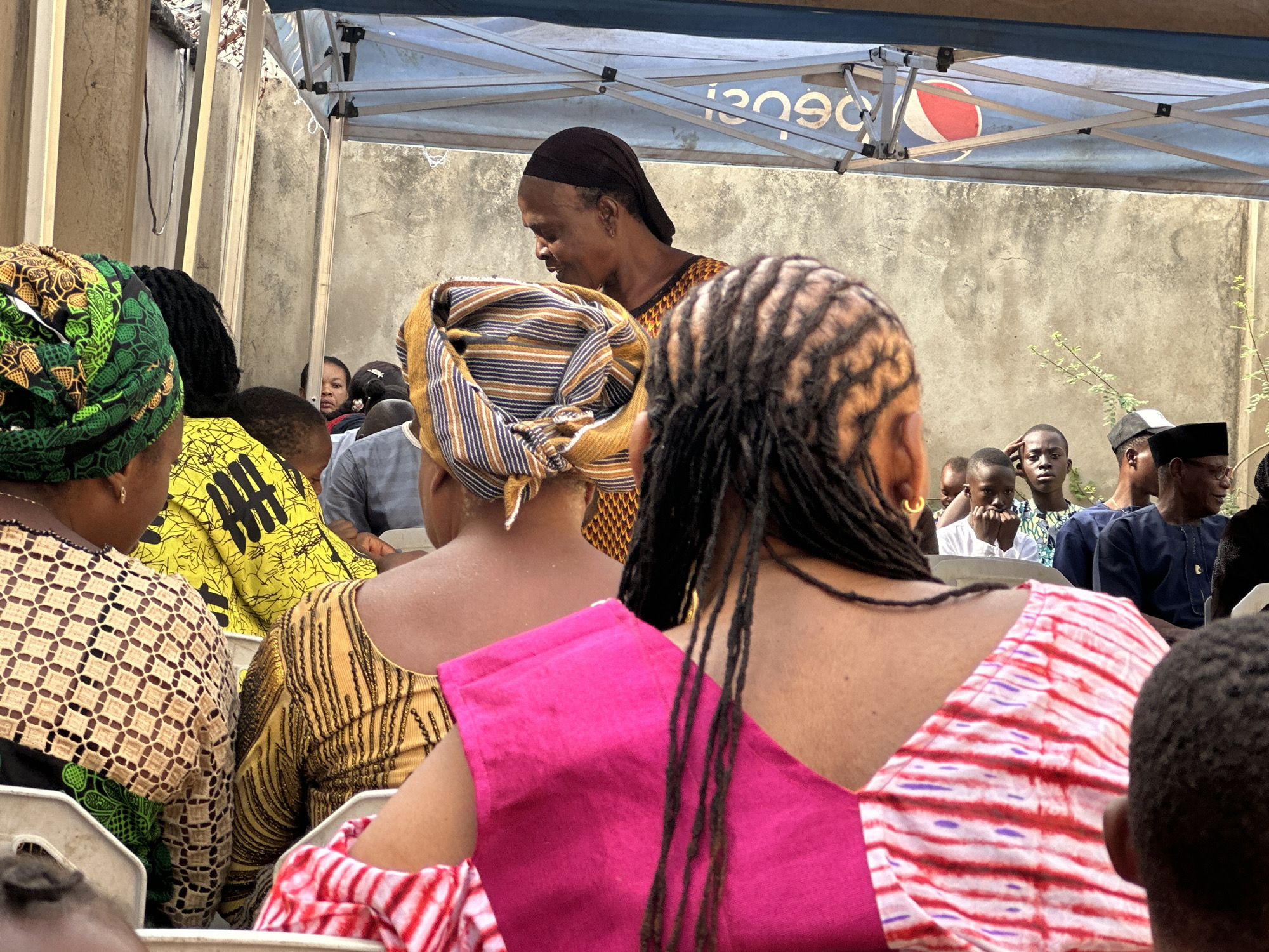 Community gathering under Pepsi canopy features traditional dress