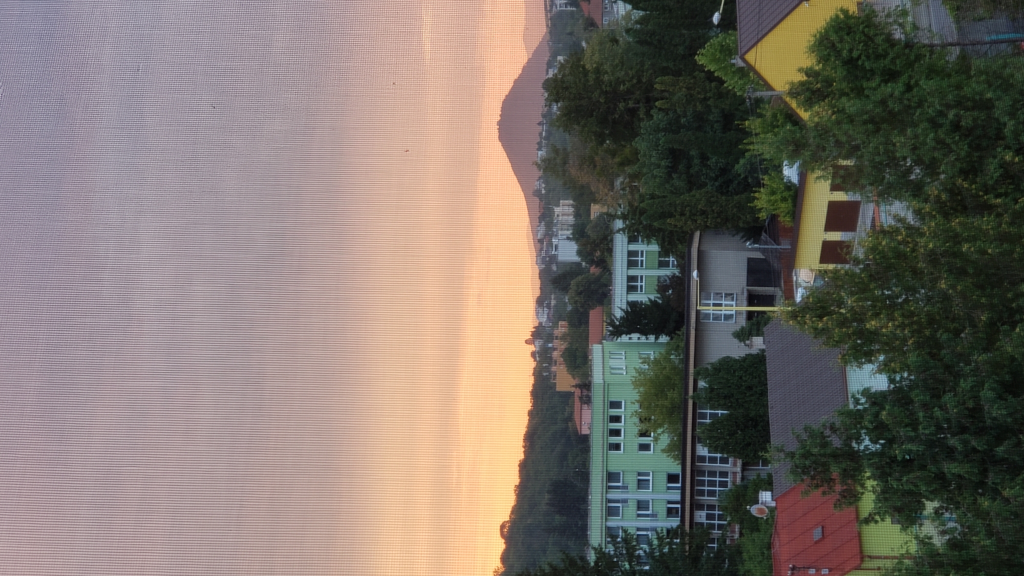 Prešov sunset watched through window screens over forested hills
