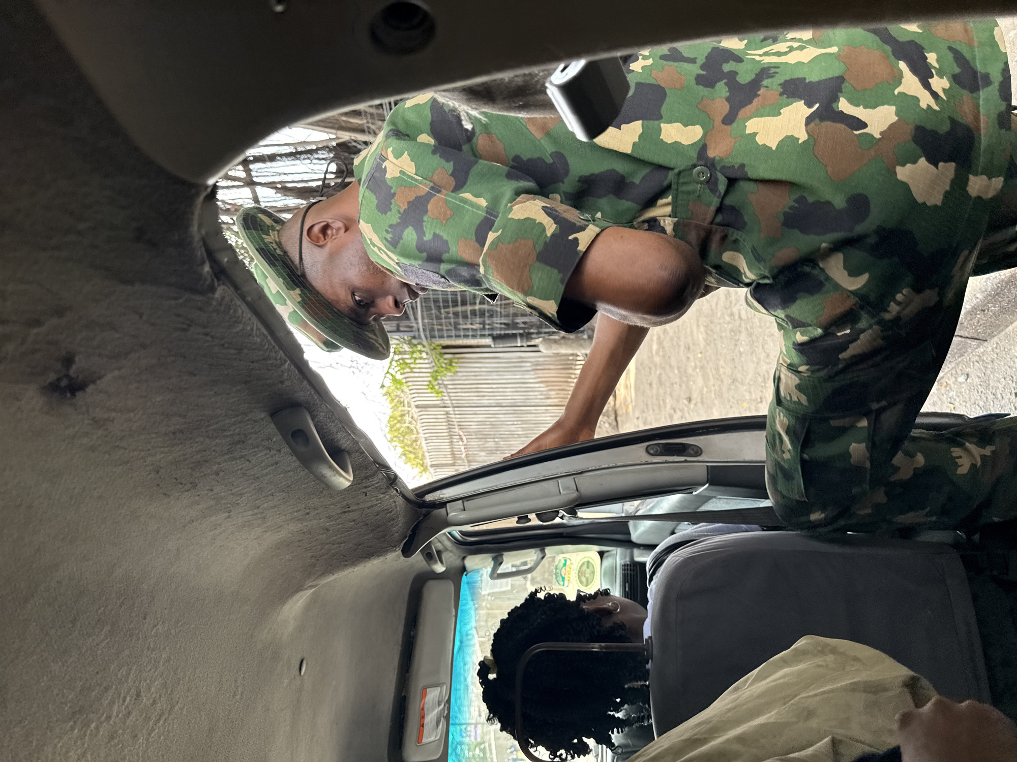 Military personnel interact with civilians near vehicle in Lagos